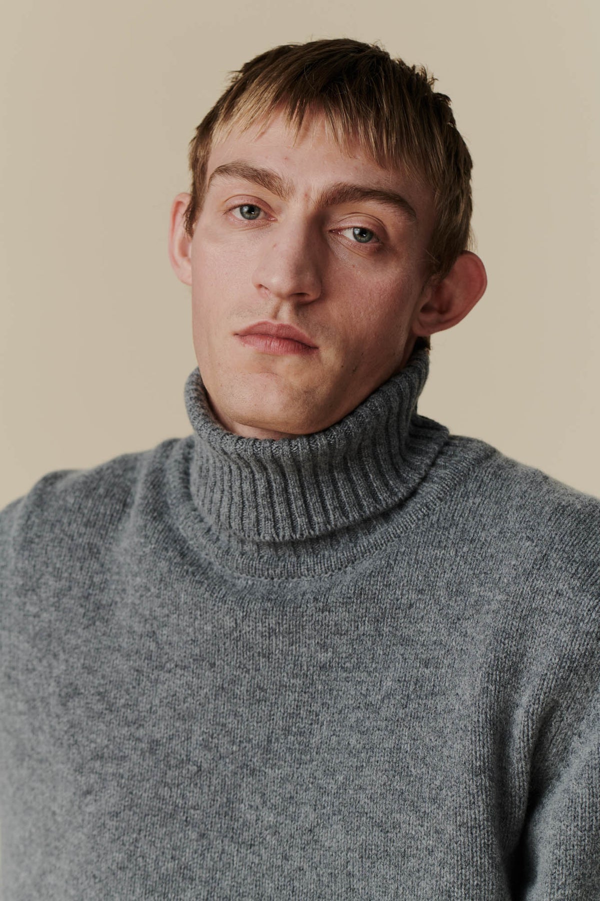 
            Portrait shot of dirty blonde, white male wearing grey roll neck jumper