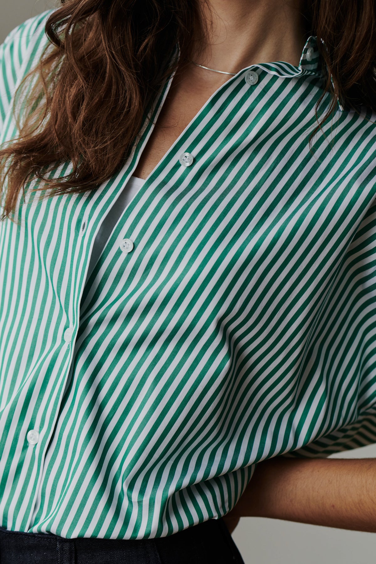 
            close up detail shot of unbuttoned green and white striped shirt