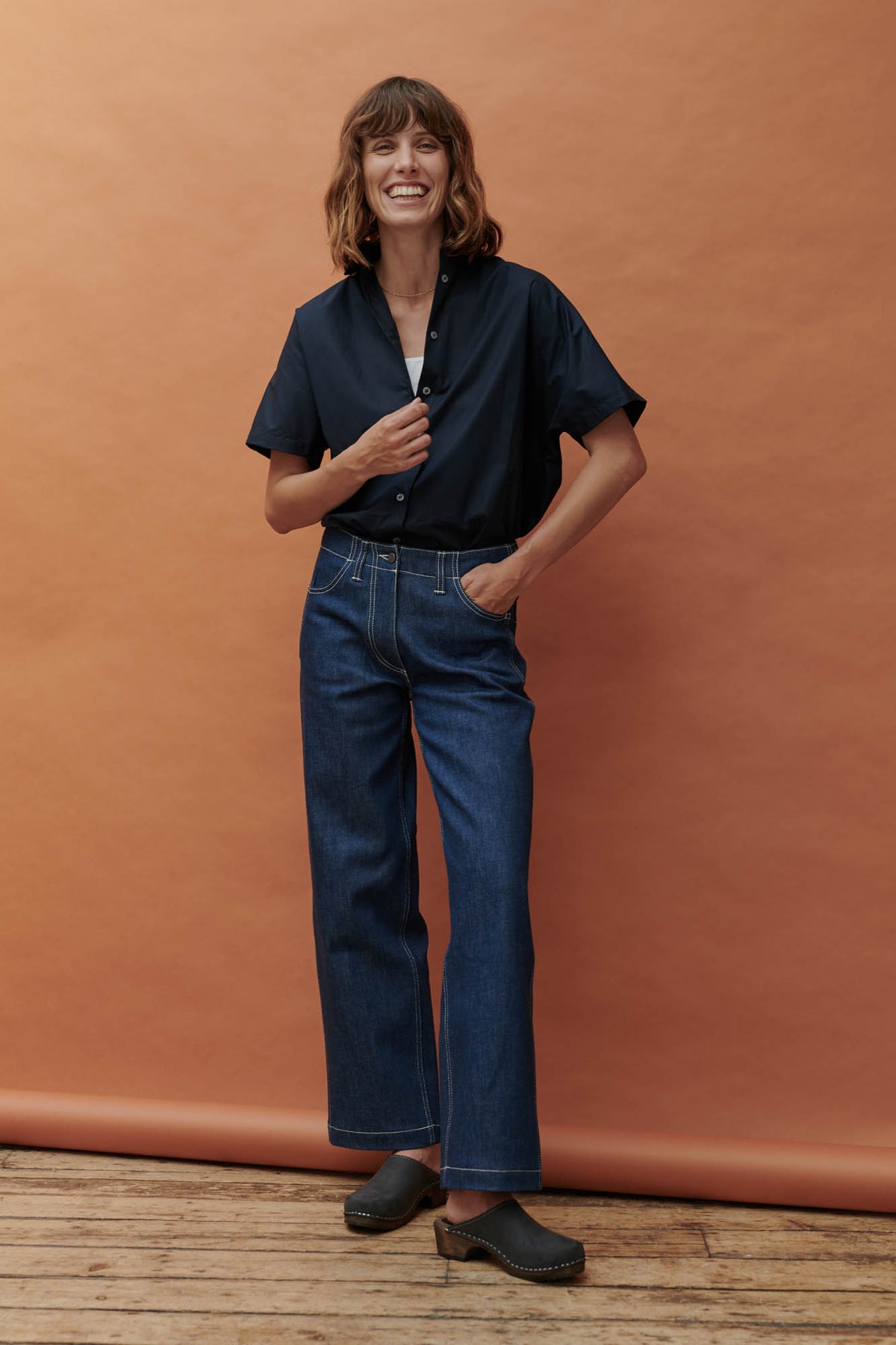 Female wearing work jean in blue paired with Ava short sleeve shirt in navy