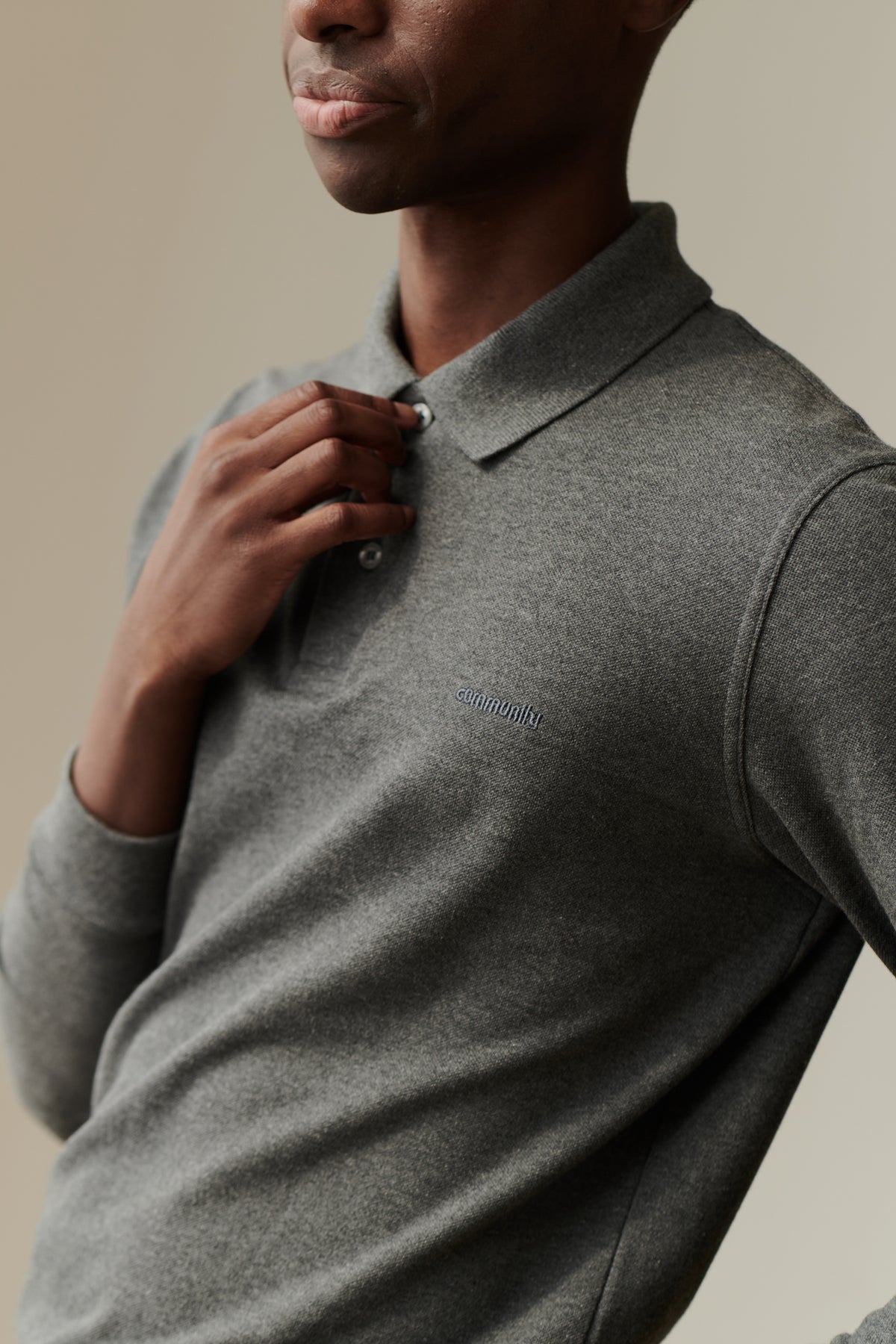 man buttoning up a grey marl polo shirt