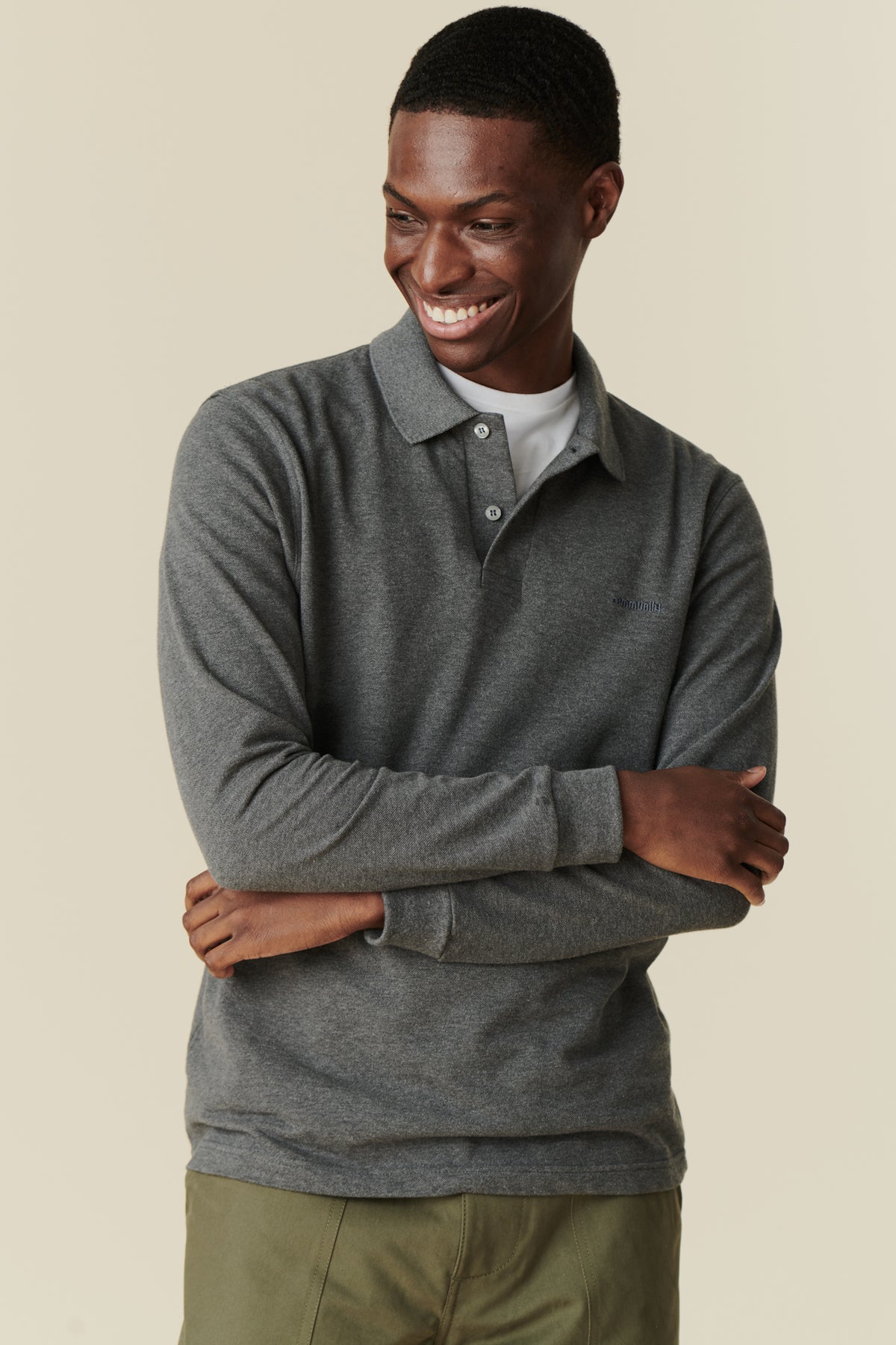 smiling male man wearing an unbuttoned grey marl polo shirt with arms folded