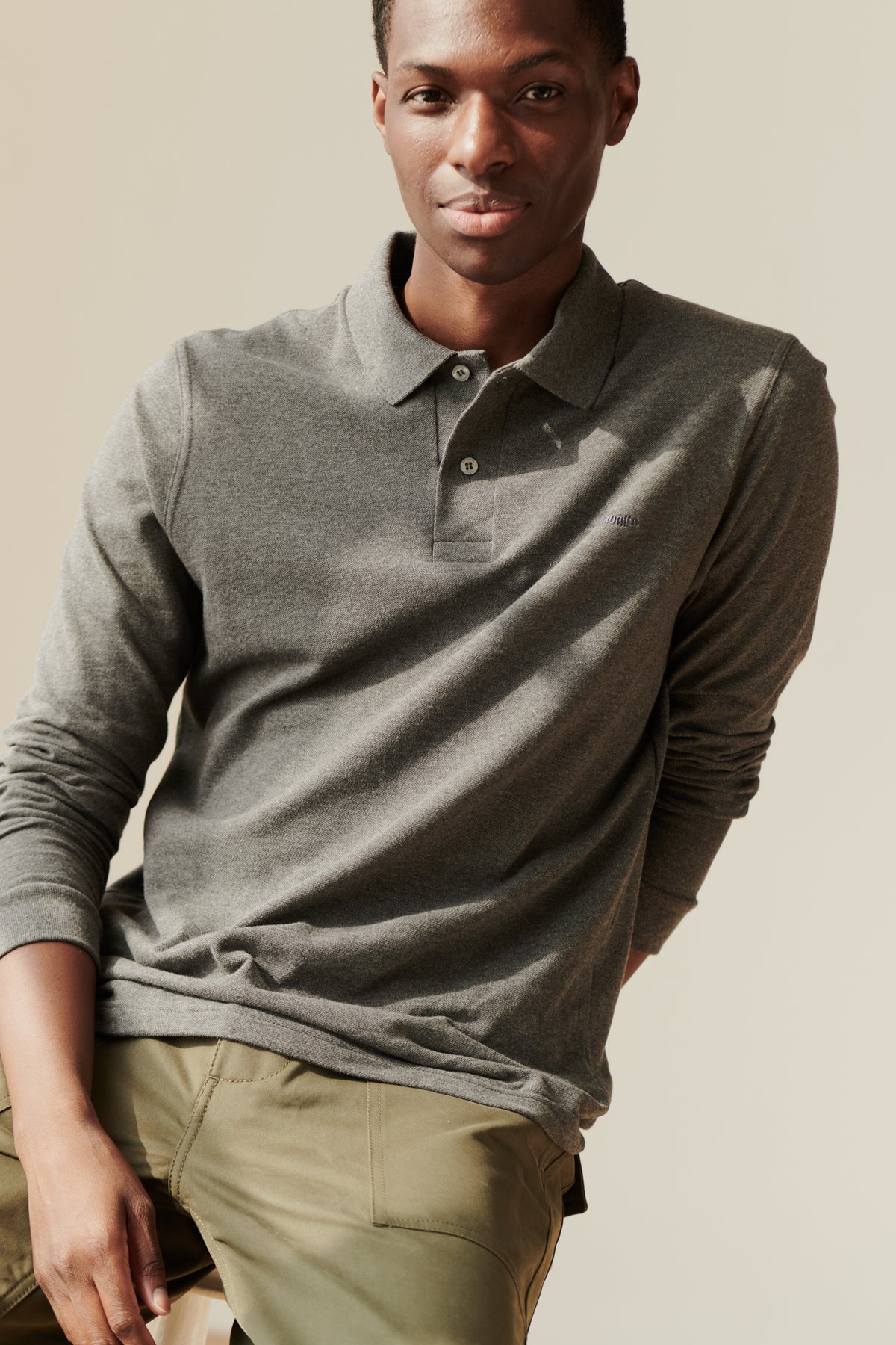 man sat on stool in a grey marl polo shirt