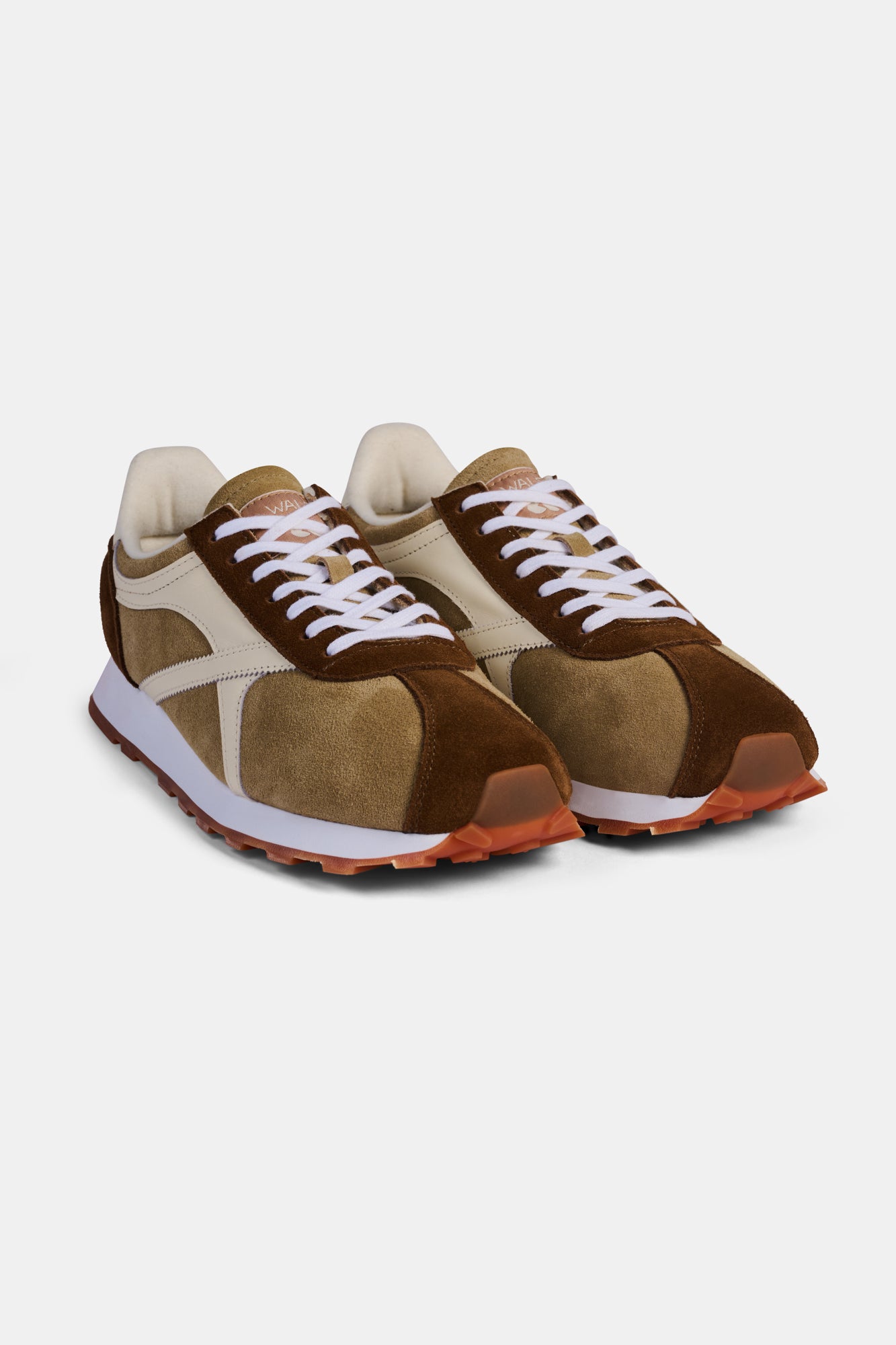 Pair of brown and beige trainers with white laces on a white background.