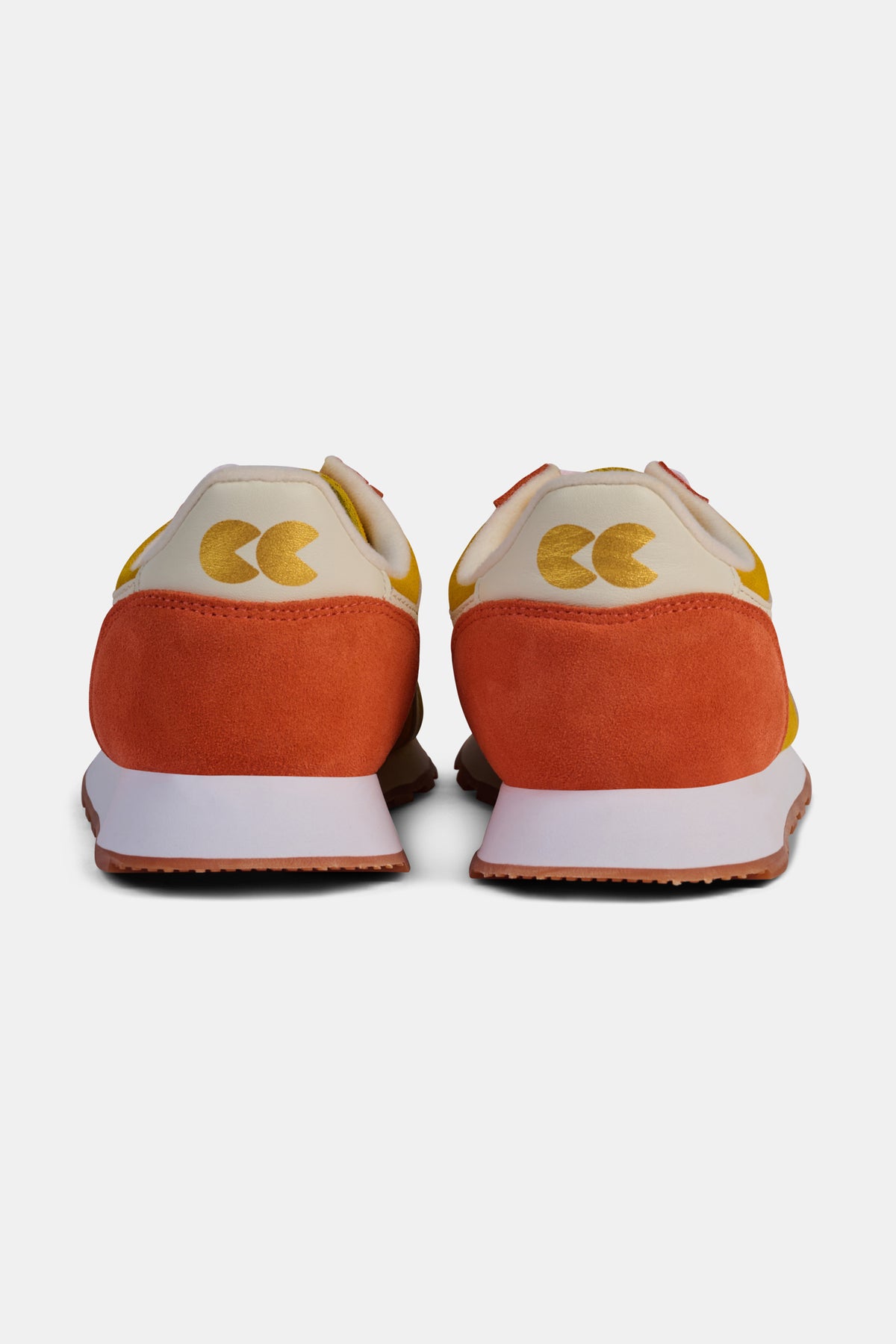 Orange trainers with white soles on a white background.