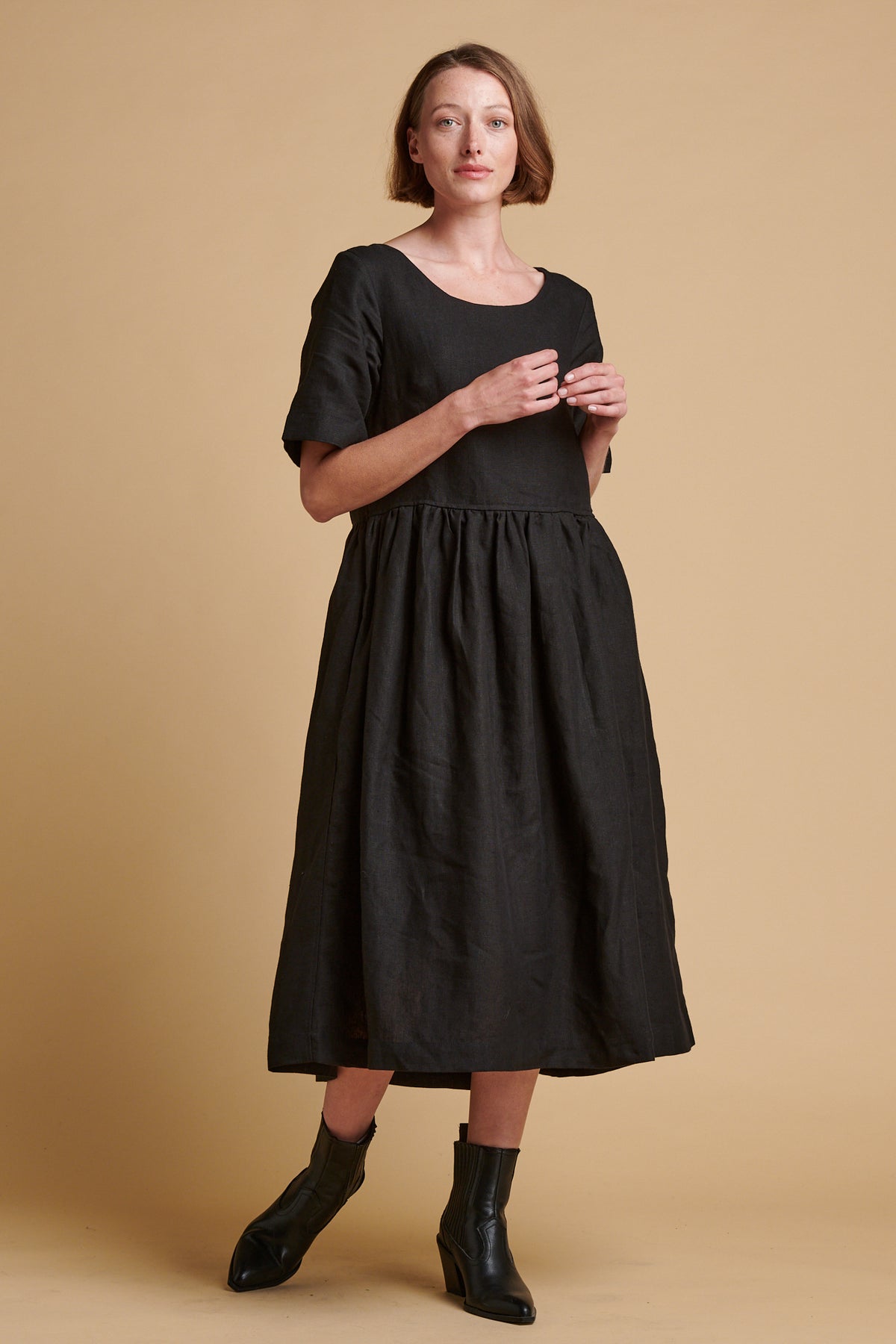 Female wearing crew neck gathered dress in black linen.