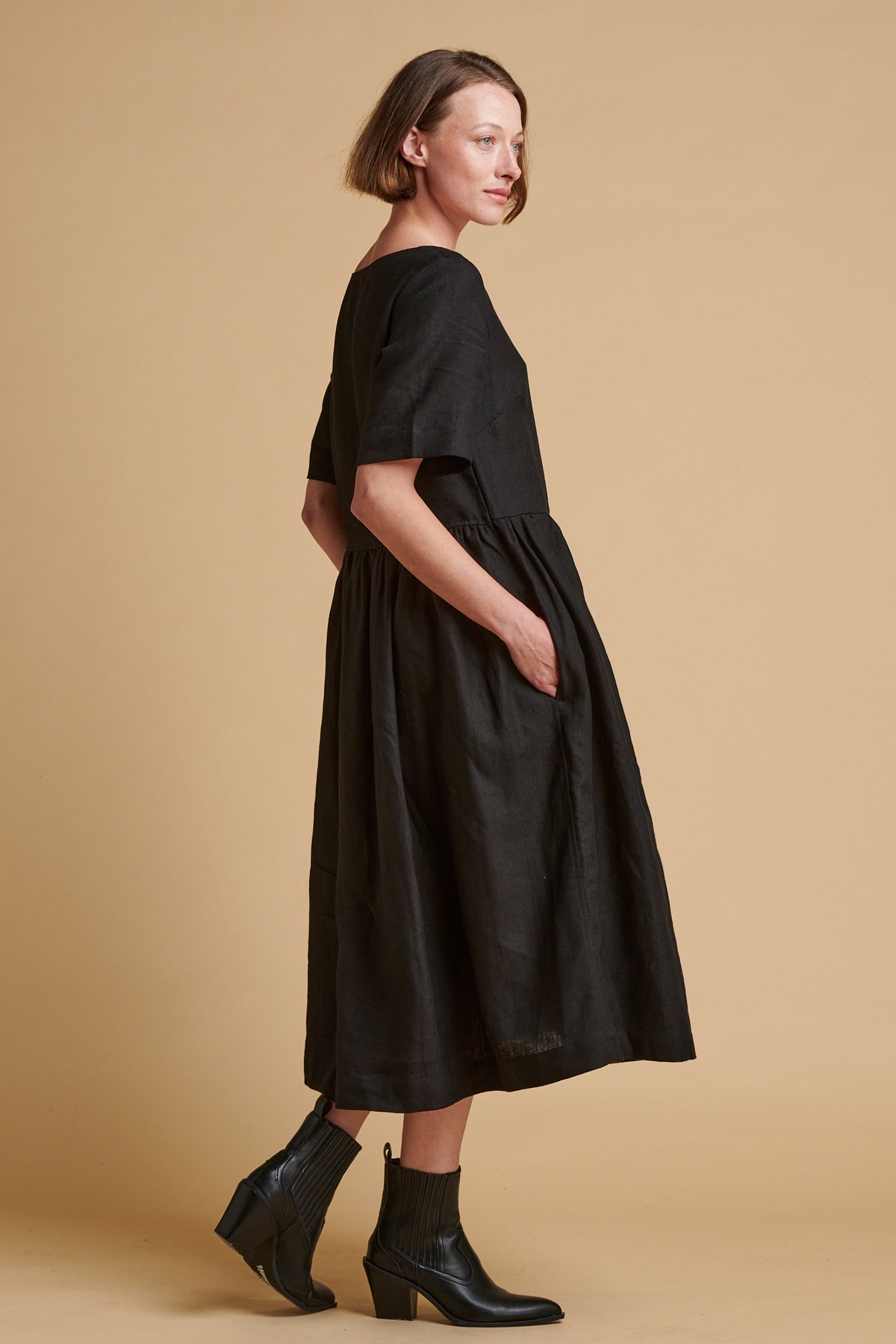 Female wearing crew neck gathered dress in black linen.