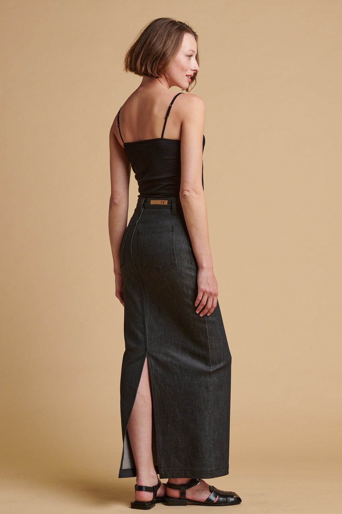 The back of Female wearing Frankie denim maxi skirt in black.