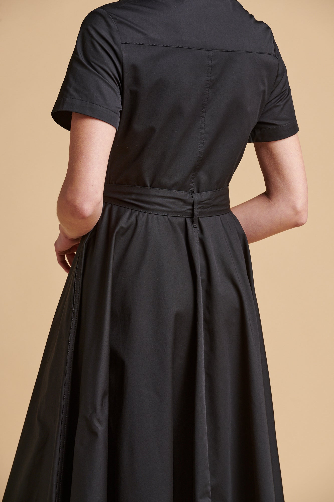 Female wearing full skirted phoebe trench dress in black.