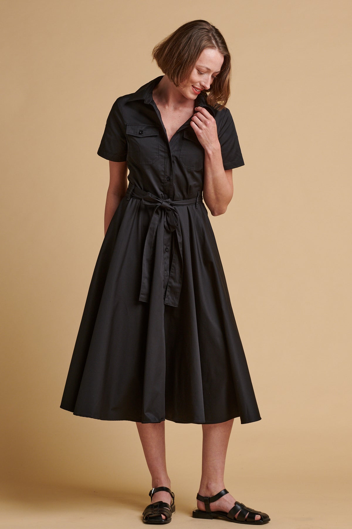 Female wearing full skirted phoebe trench dress in black.
