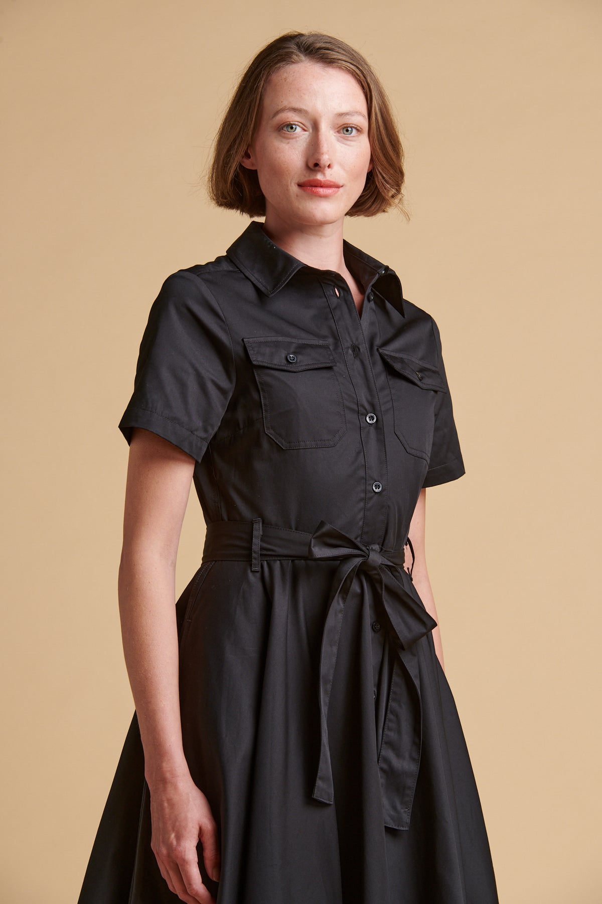 Female wearing full skirted phoebe trench dress in black.