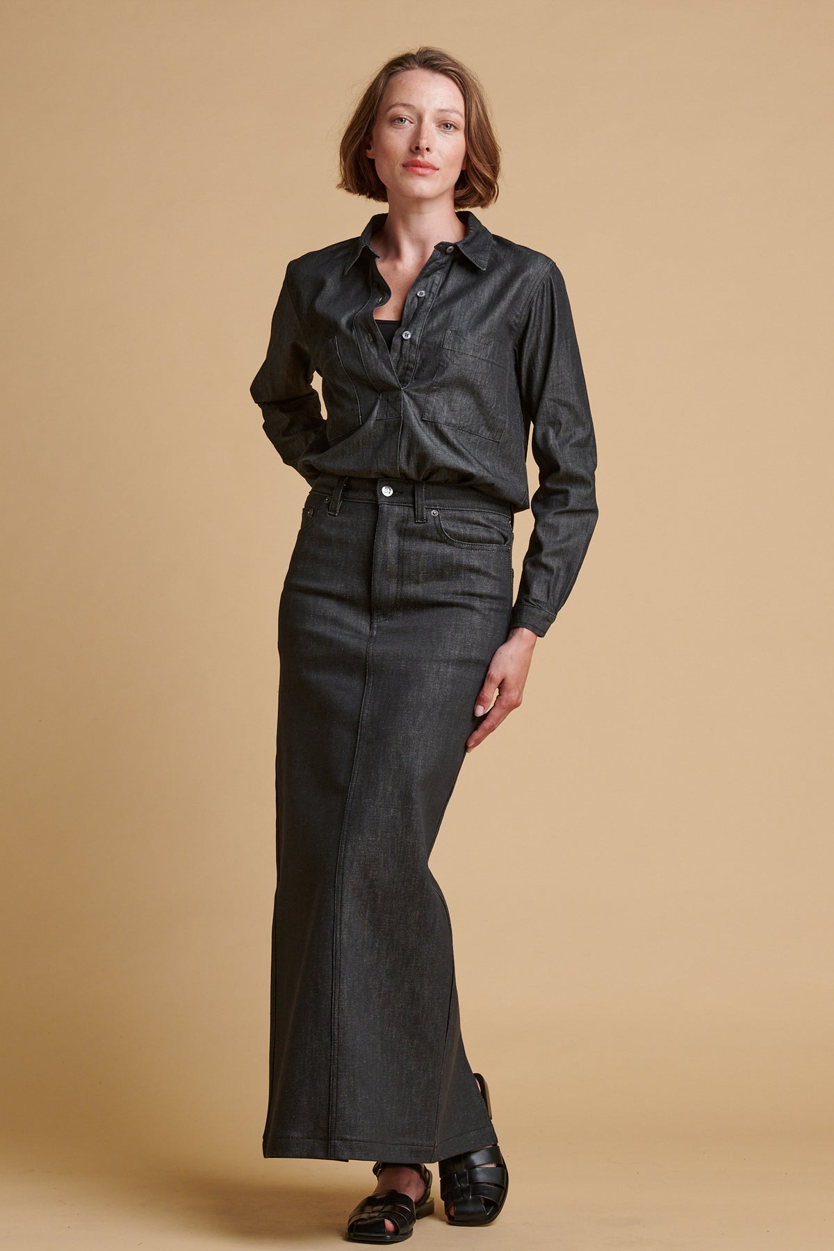 Female wearing Olivia half placket lightweight denim shirt in black paired with Frankie denim maxi skirt in back.