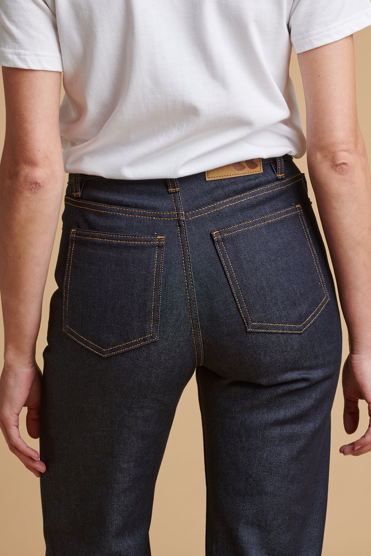 Detail shot of the back of female wearing wide leg high rise denim jean in indigo paired with classic short sleeve t shirt in white.
