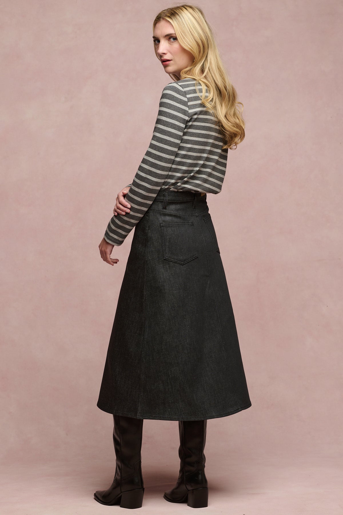 Full body image of the side female wearing Bobbie a line denim skirt in black with black boots