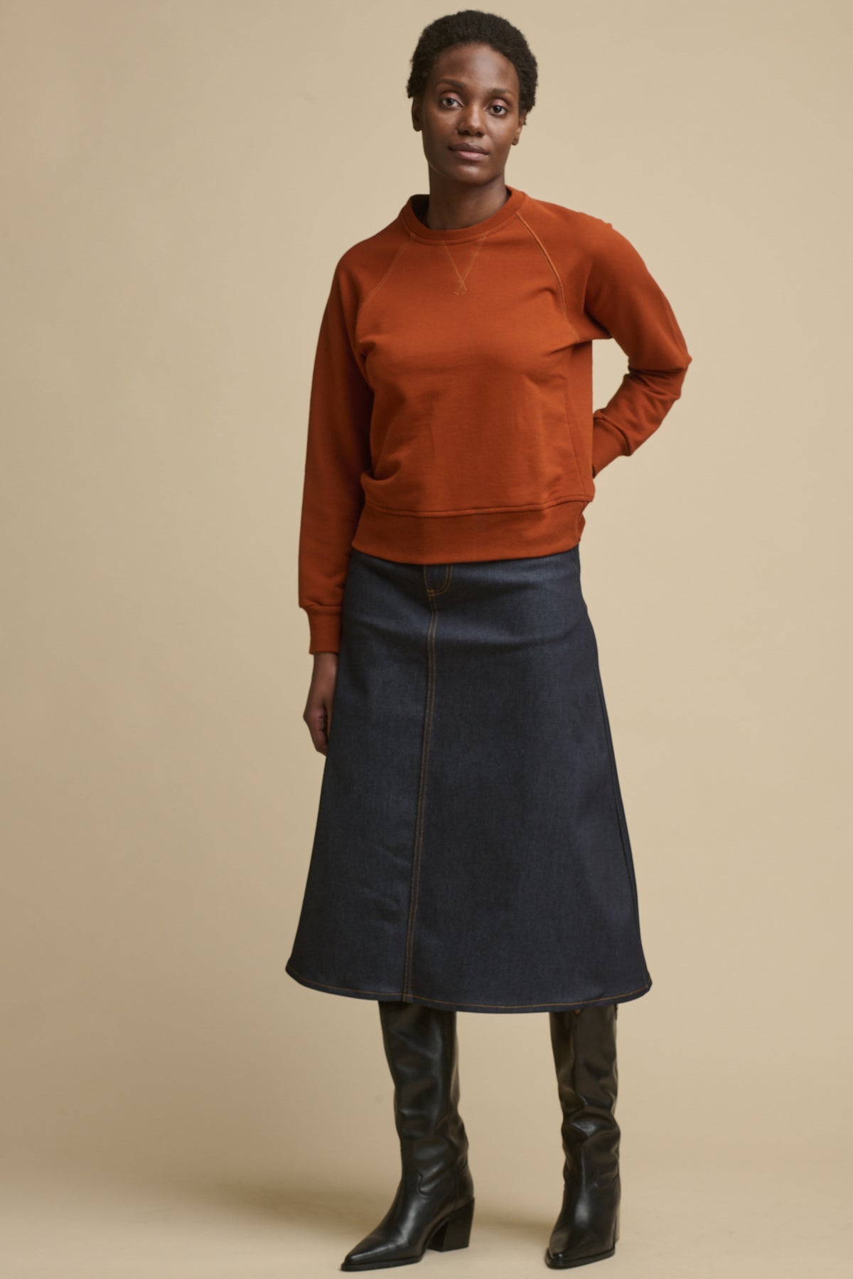 
            Full body image of the front of black female wearing Bobbie a line denim skirt in indigo paired with cinnamon raglan sweatshirt