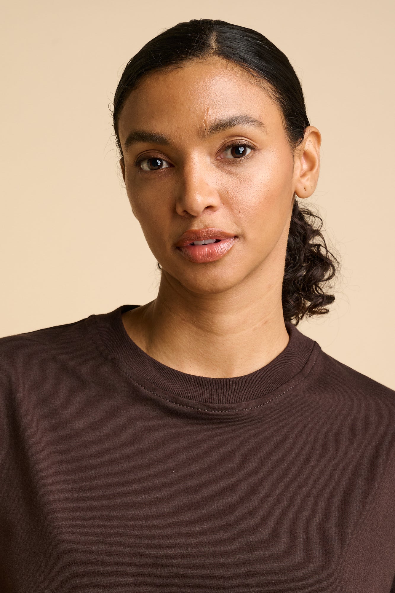 Woman wearing a brown shirt against a beige background