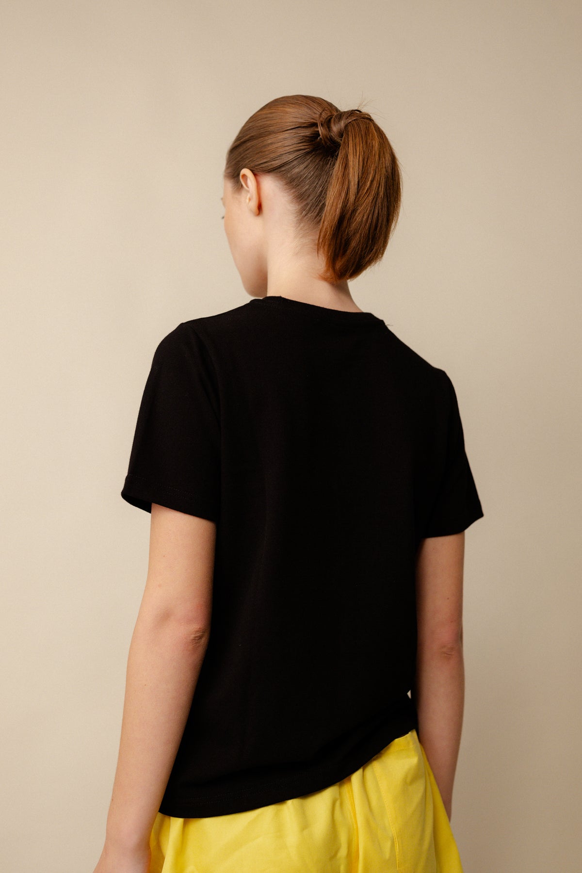 Back of white female wearing breathable short sleeve t shirt in black with CCOA logo