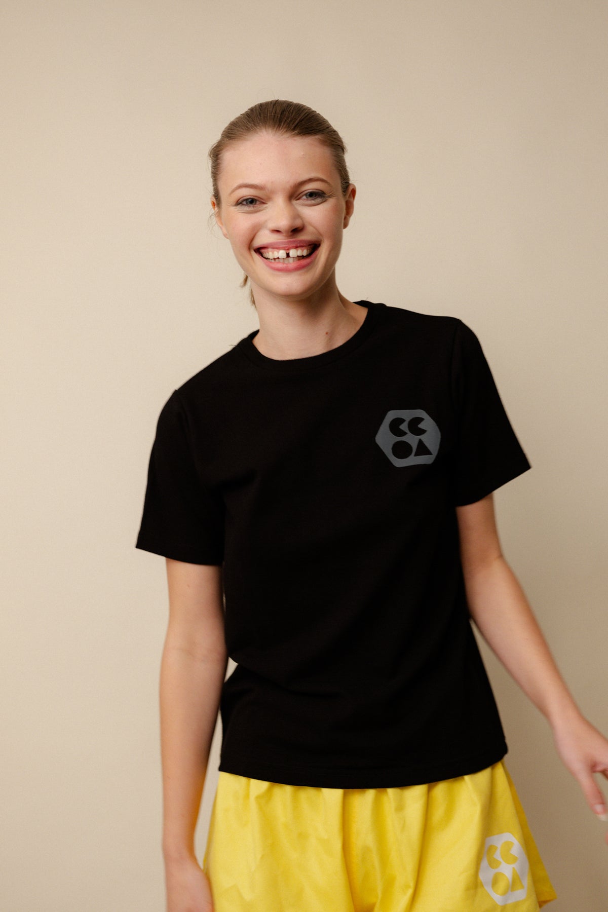Smiley, white female wearing breathable t shirt plastic free in black with CCOA logo