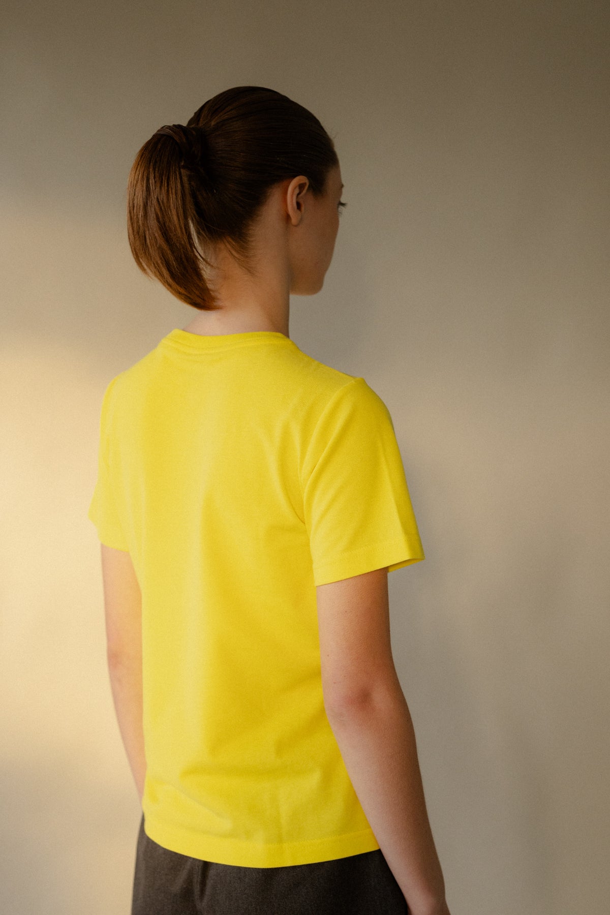 Image of the back of female wearing women's breathable short sleeve t shirt plastic free in canary yellow