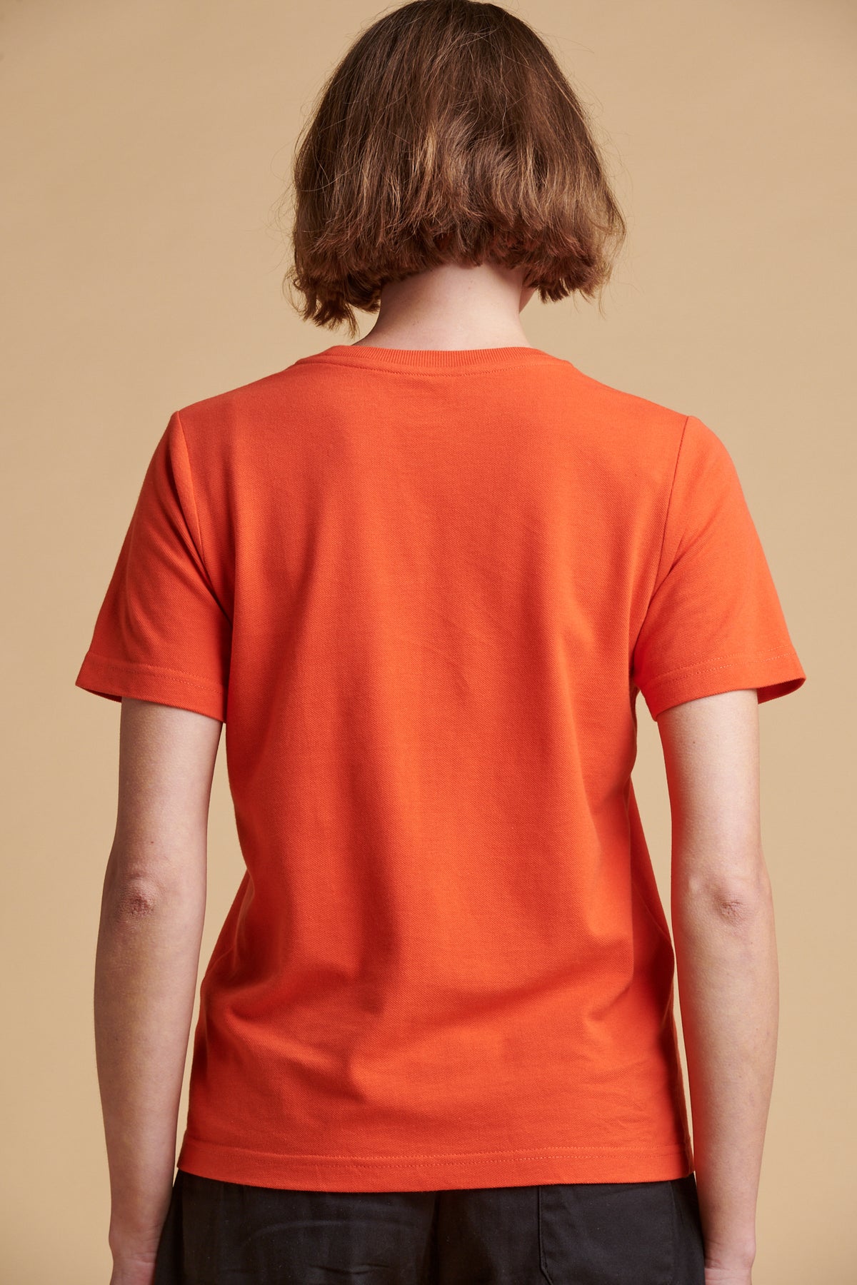 The back of female wearing breathable t shirt in flame red.