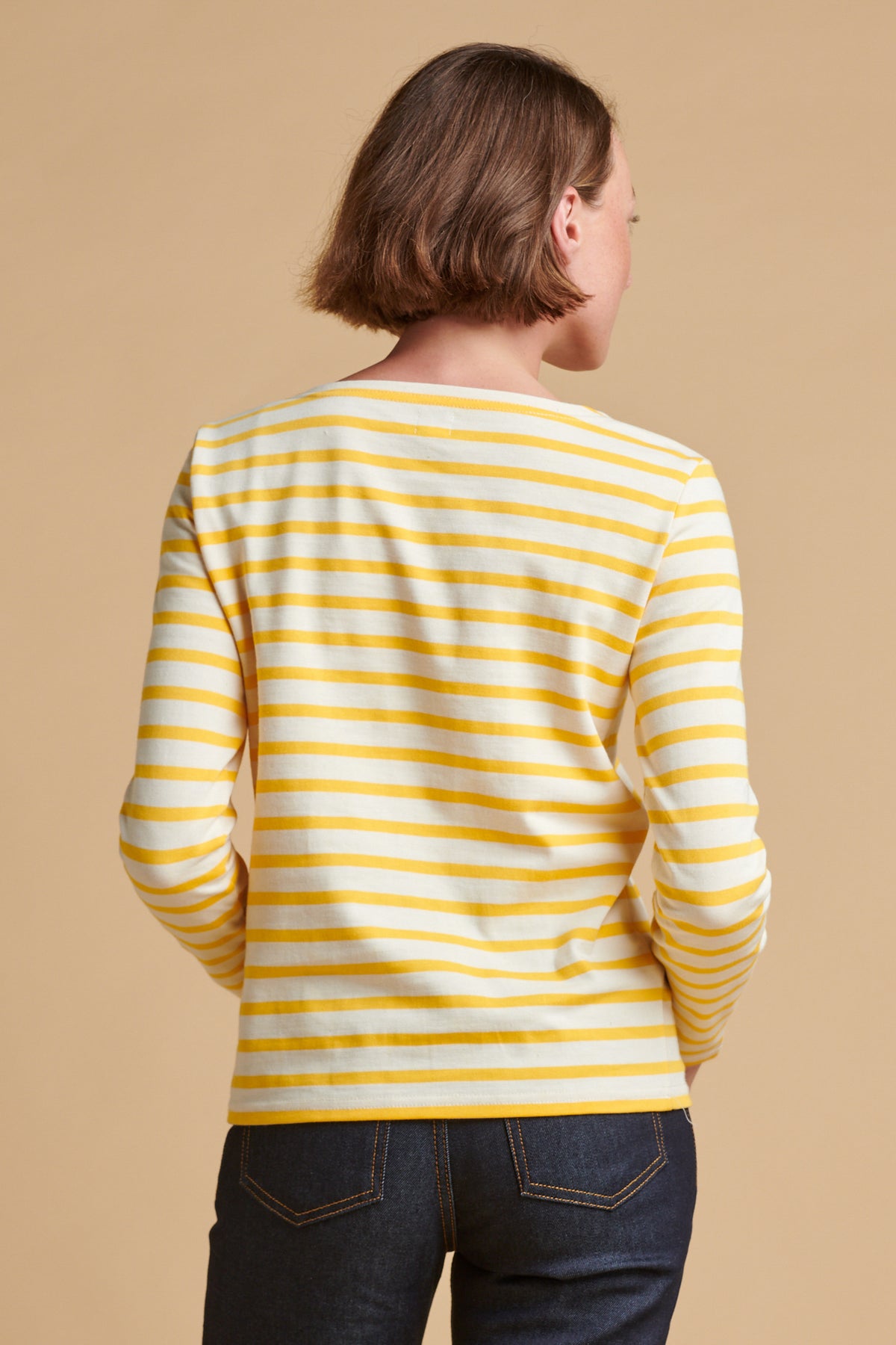 The back of female wearing long sleeve Breton top in ecru yellow.