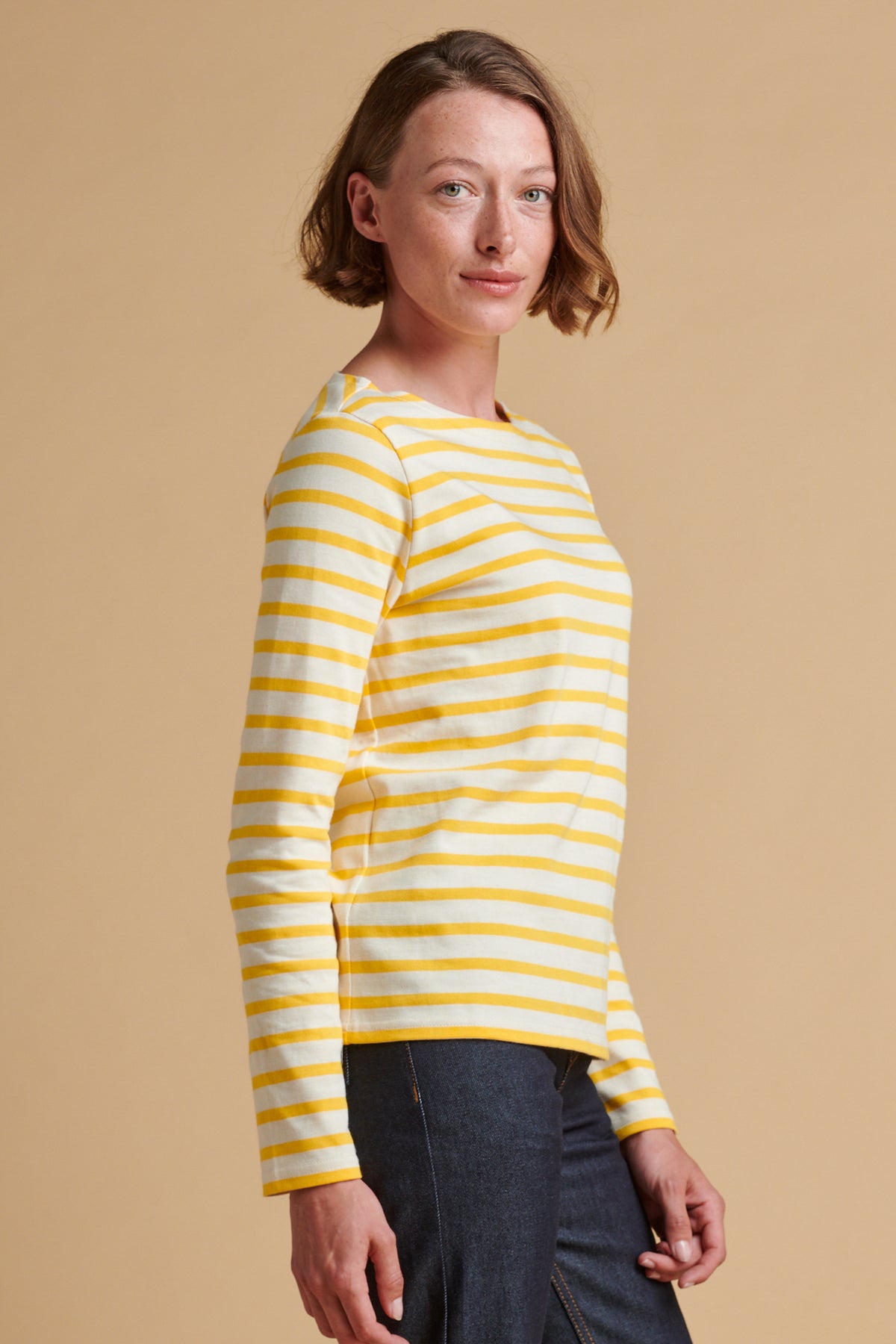 Female wearing long sleeve Breton top in ecru yellow.