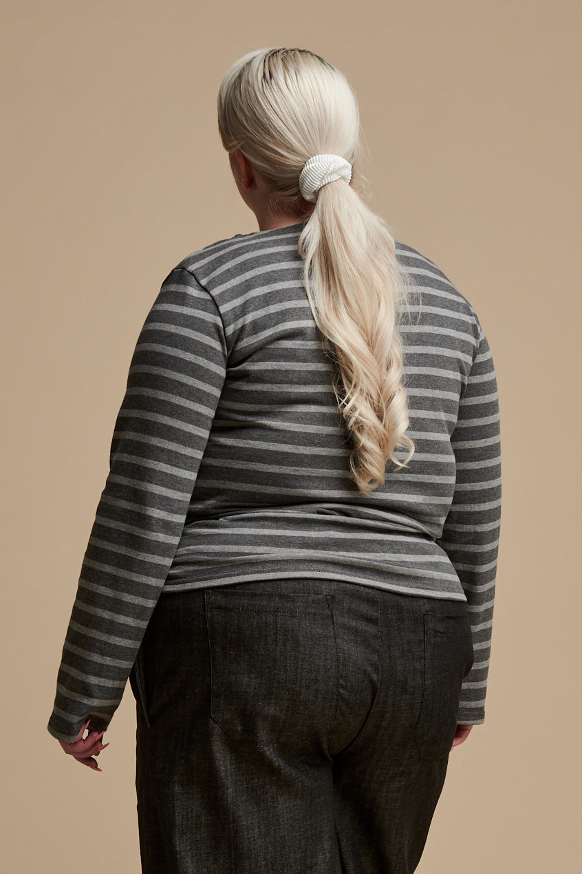 The back of female with long blonde hair tied into a pony tail wearing long sleeve Breton top in charcoal marl and grey marl stripe