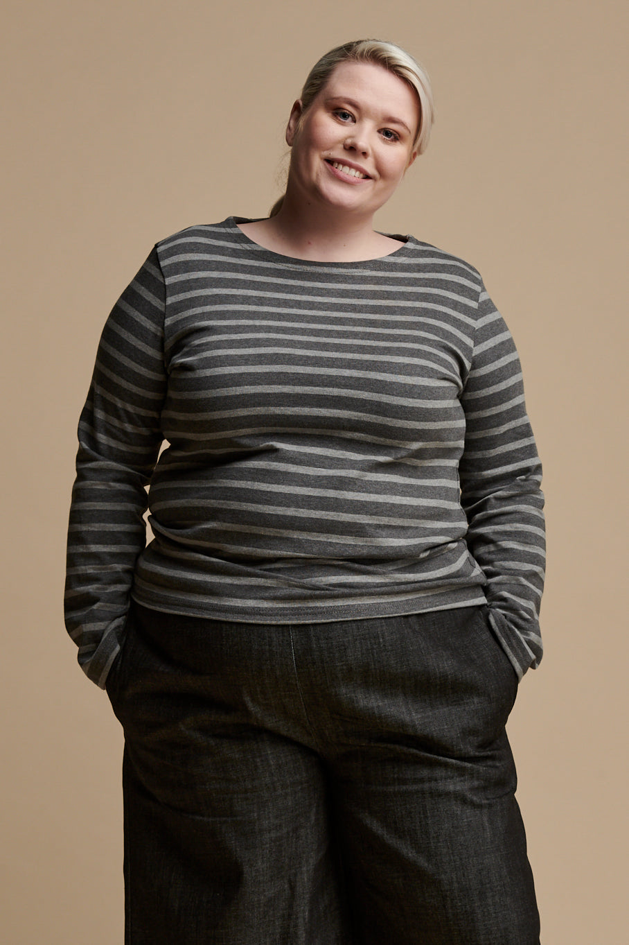 
            Blonde female with hair tied back wearing long sleeve Breton top in charcoal marl and grey marl stripes paired with black denim pants