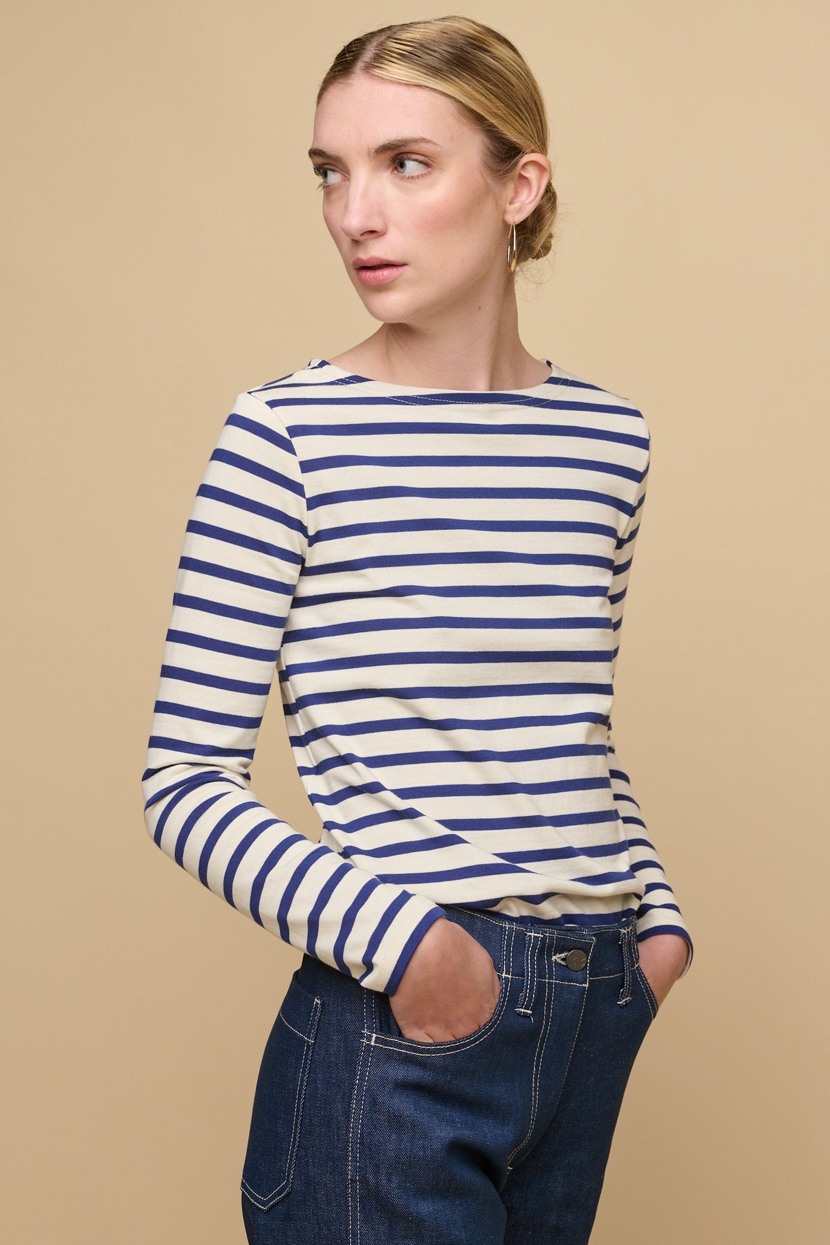 Thigh up image of female wearing Breton in ecru/bright blue tucked into women's work jeans in blue