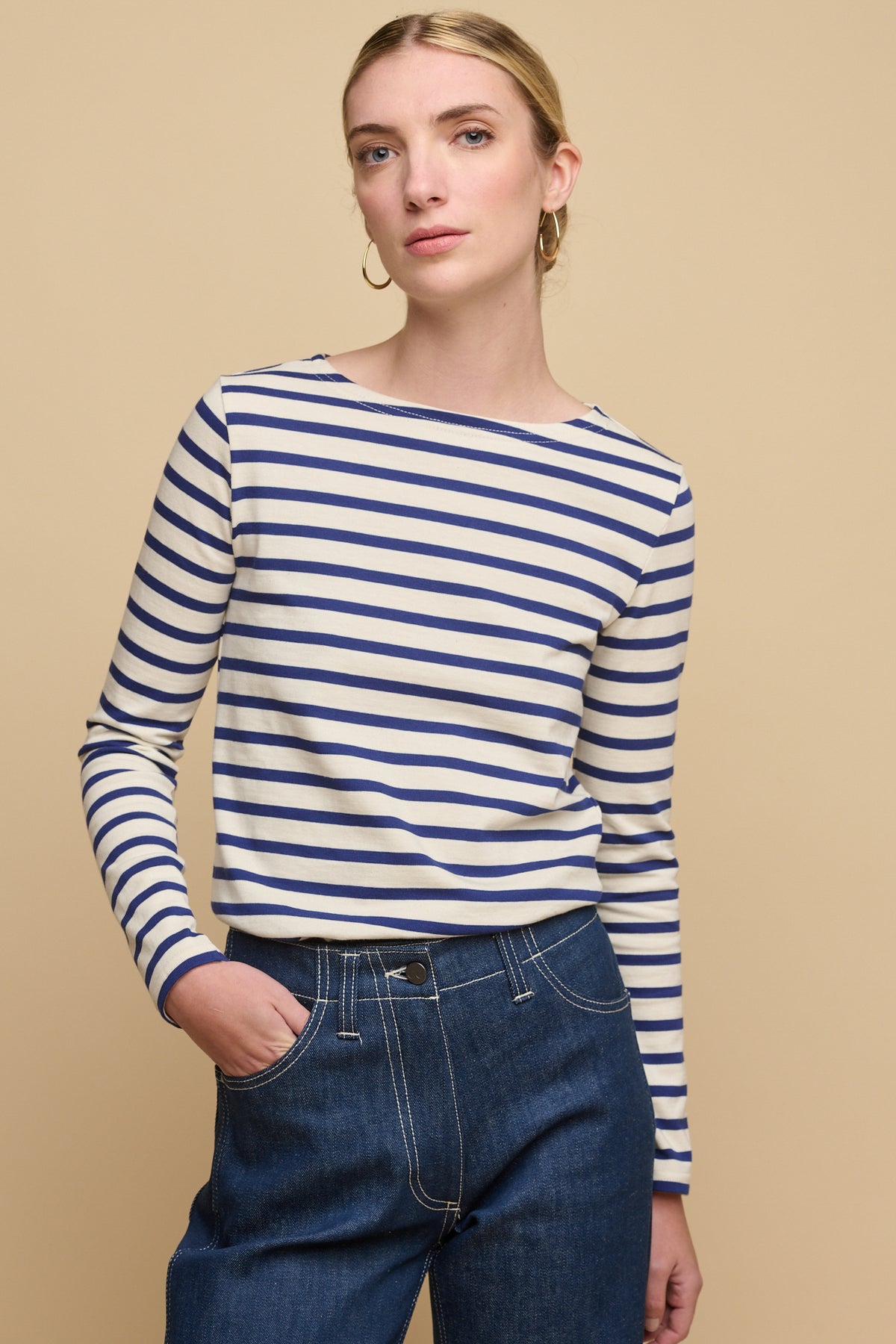 Thigh up image of the front of female wearing Breton in ecru/bright blue tucked into women's work jeans in blue