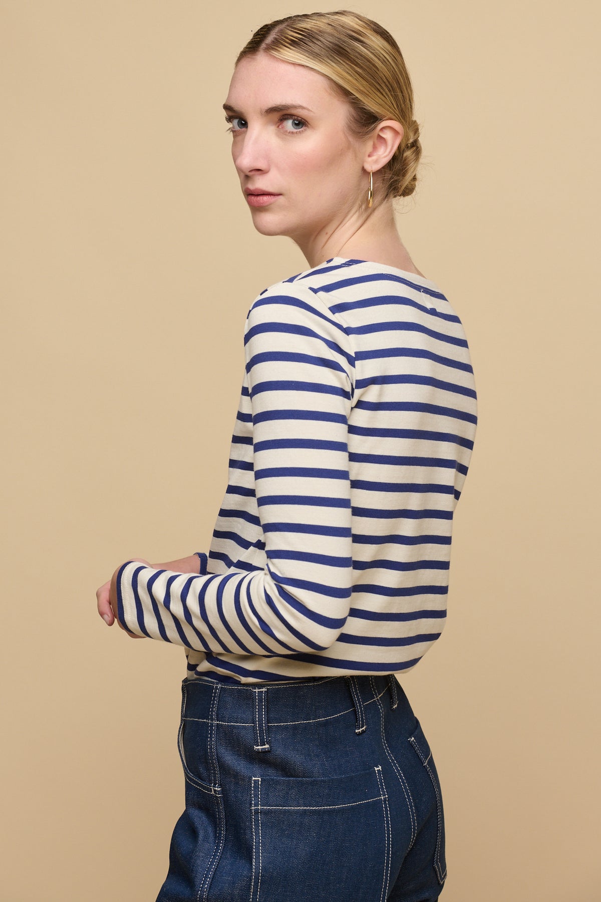 Thigh up image of the side of female wearing Breton in ecru/bright blue tucked into women's work jeans in blue