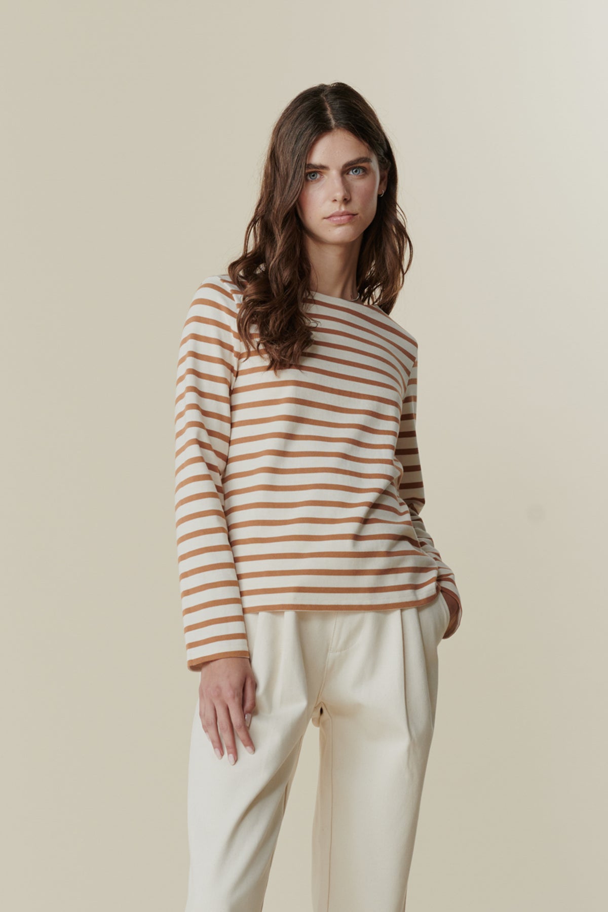 
            Brunette female wearing Breton in ecru cinnamon stripe paired with pleated jeans in ecru