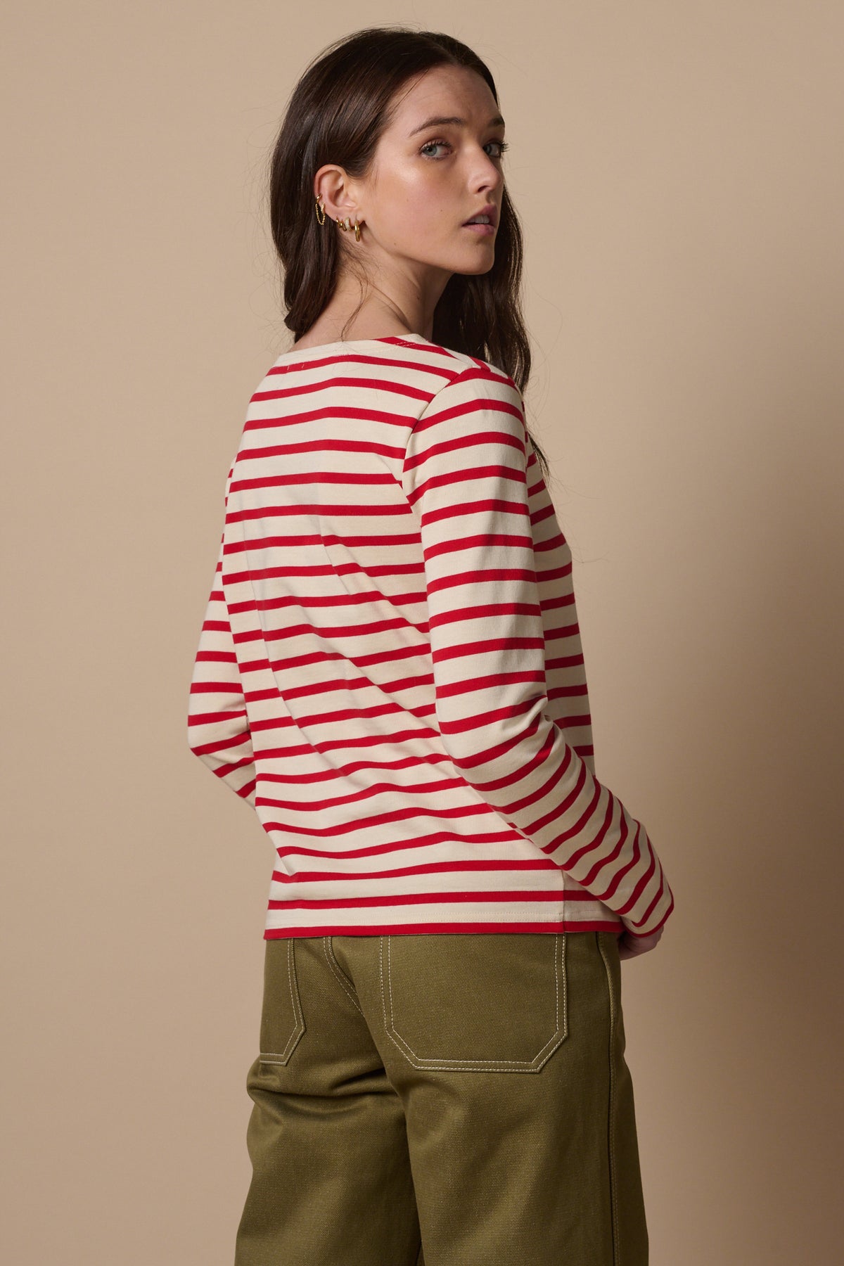 
            The back of white female with long brunette hair wearing Breton in ecru and red