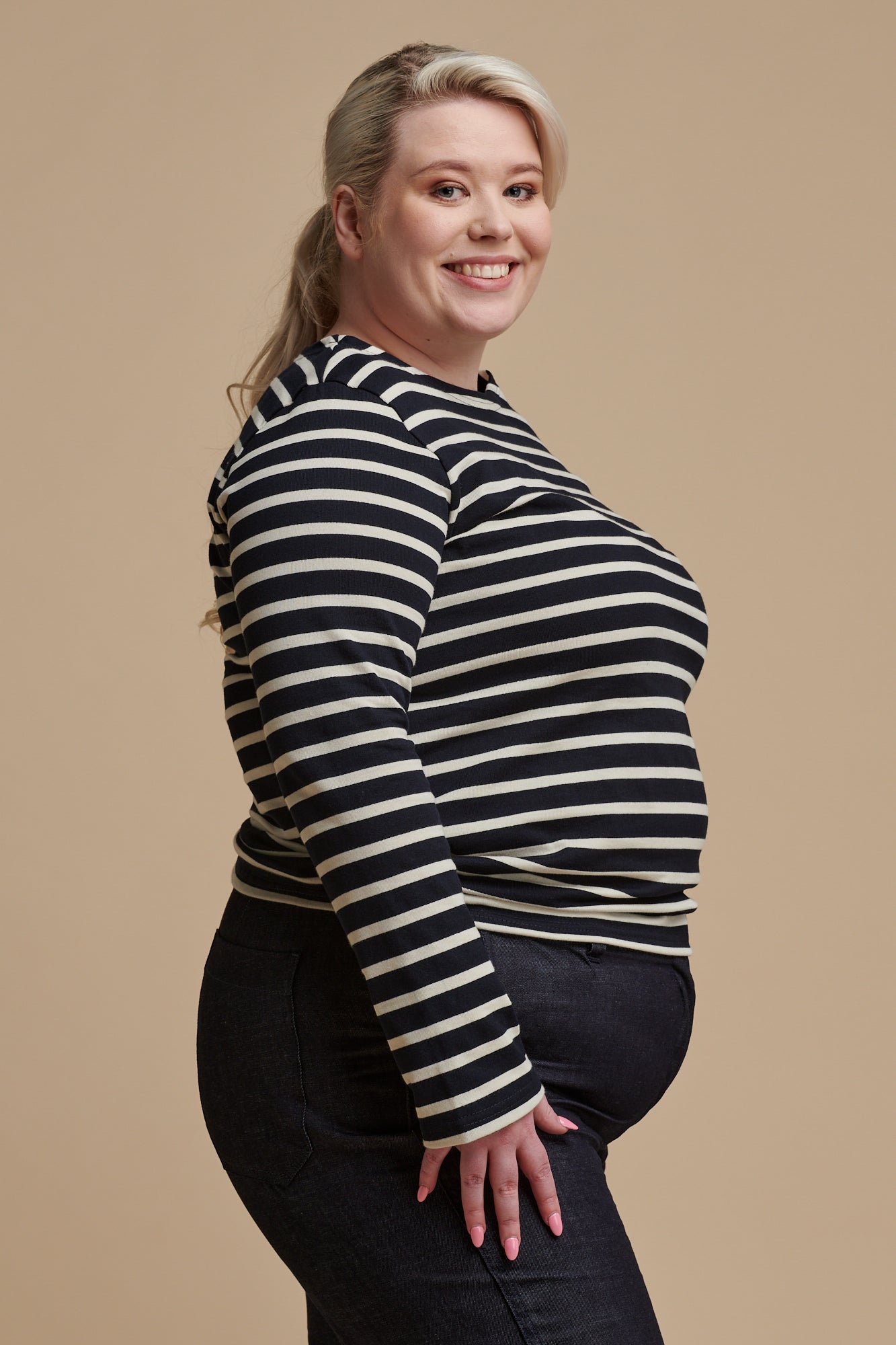 Thigh up of the side of female wearing long sleeve Breton top in navy ecru stripe paired with work trousers in indigo denim 