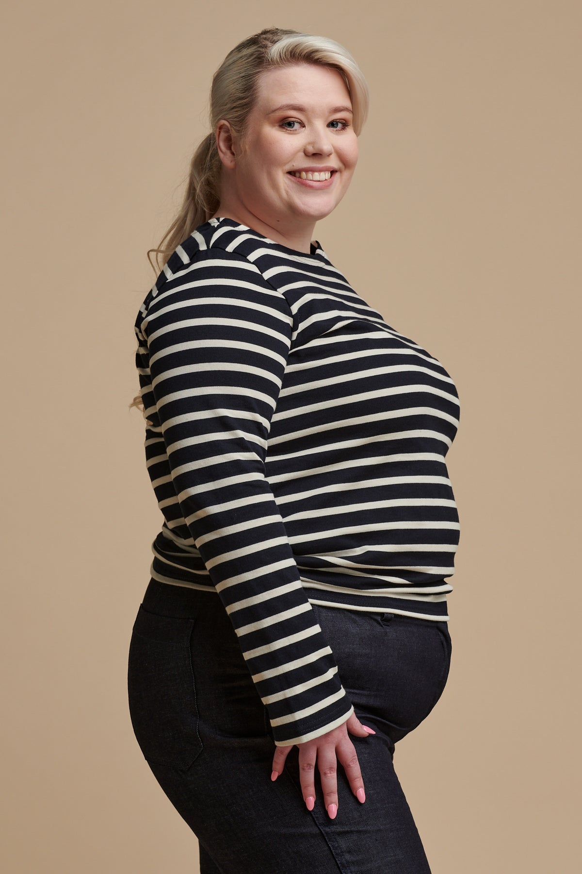 
            Thigh up of the side of female wearing long sleeve Breton top in navy ecru stripe paired with work trousers in indigo denim 