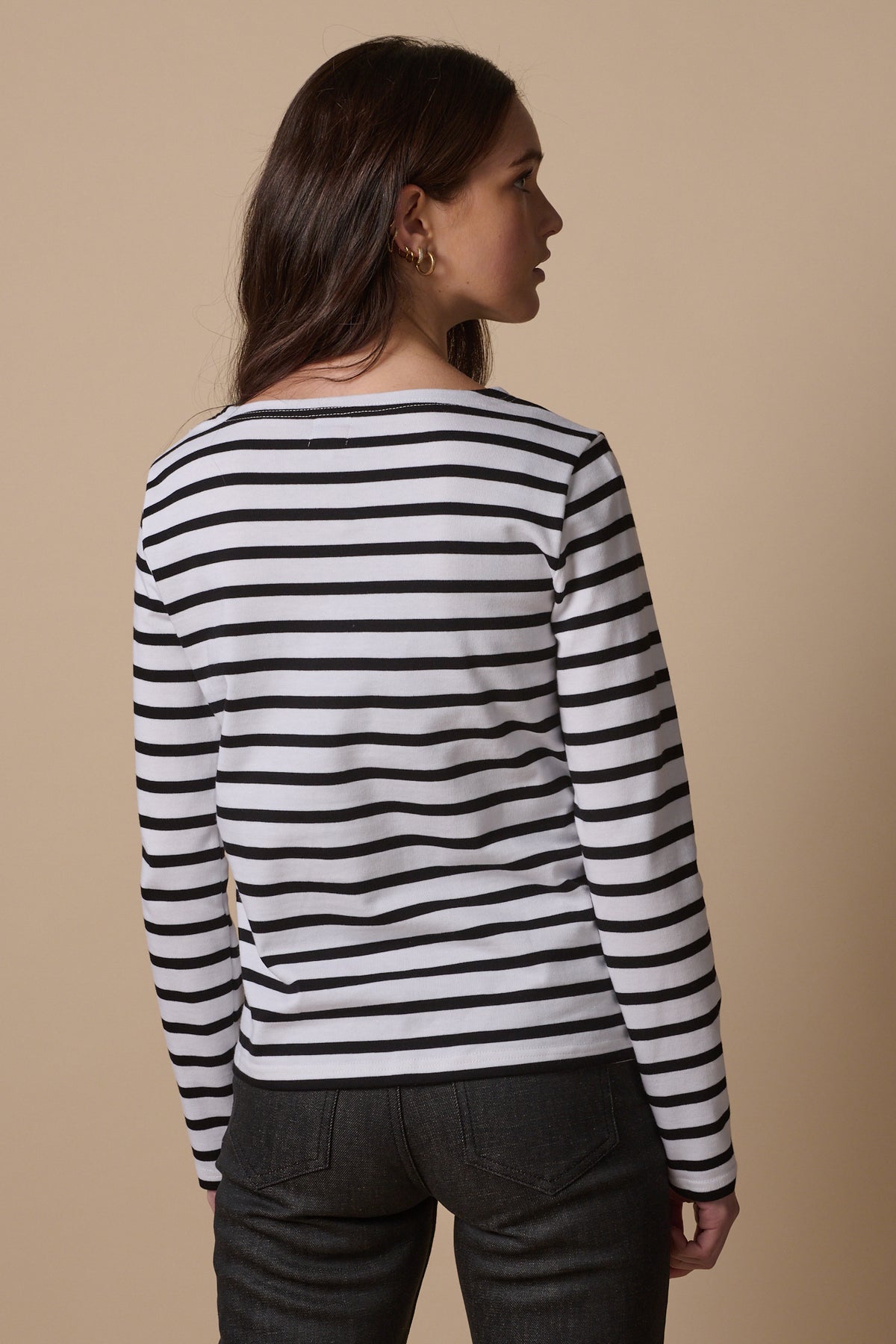 Thigh up image of the back of female wearing long sleeve Breton in white and black