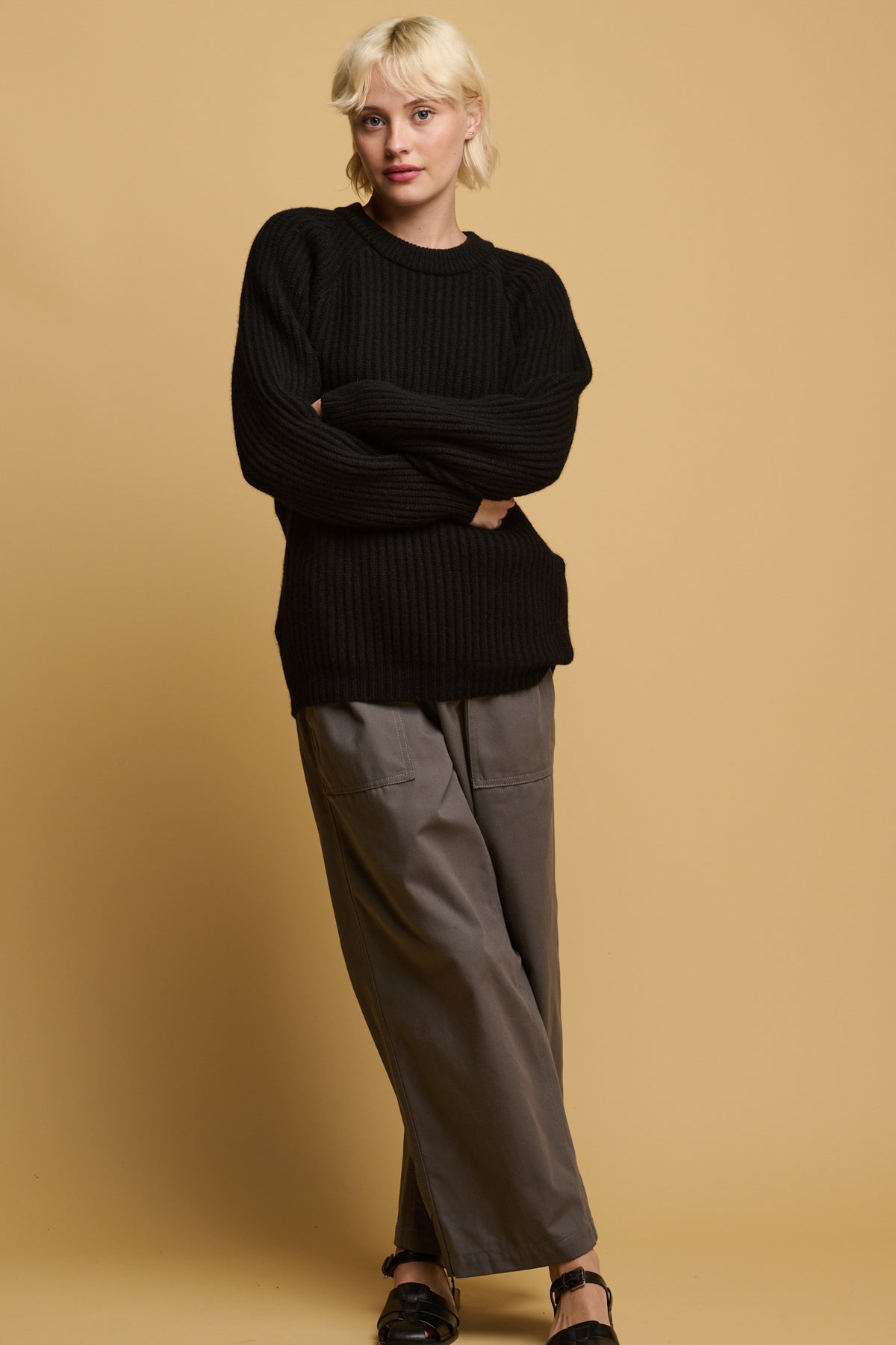 The front of blonde female with her arm crossed wearing camerawoman trousers in charcoal