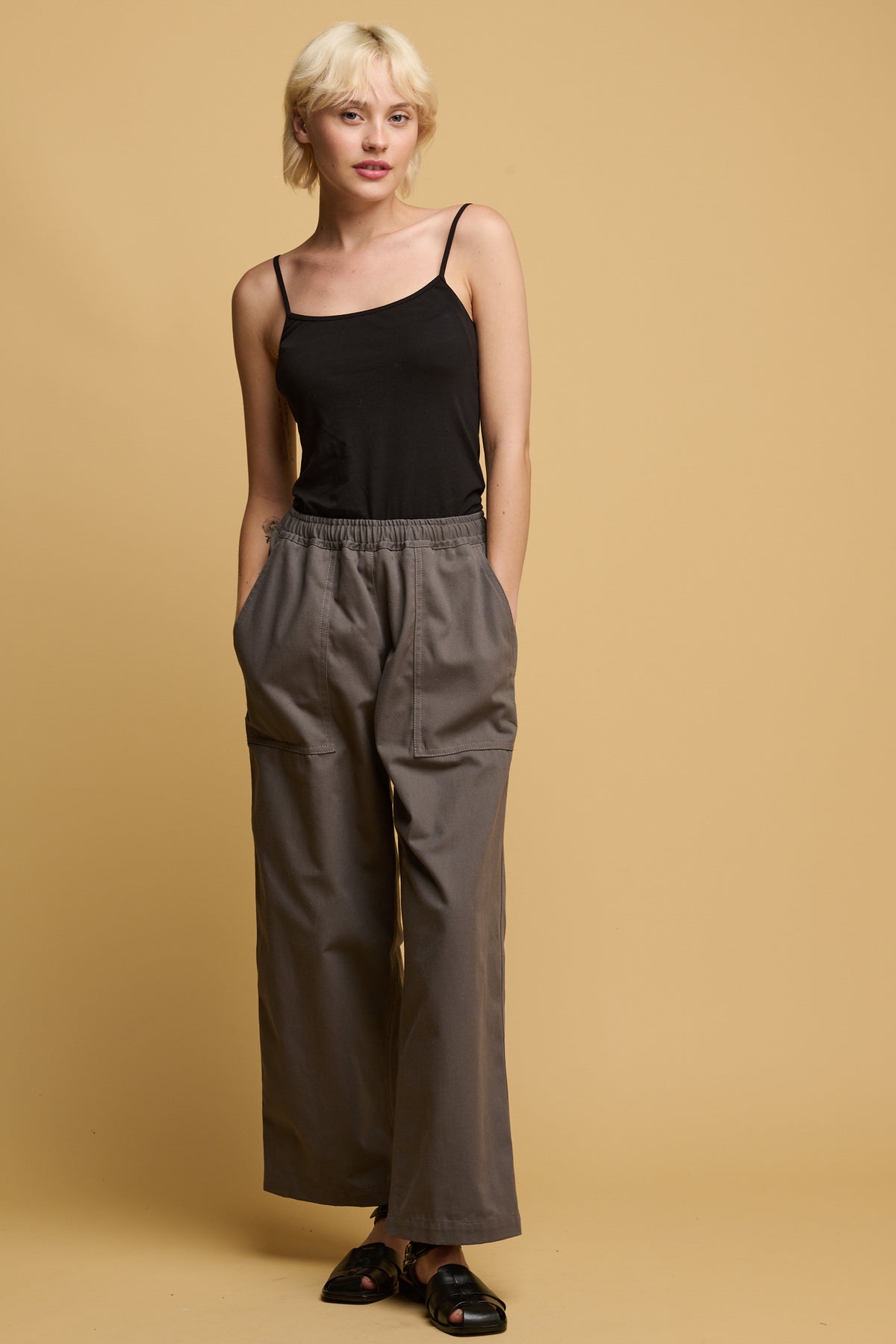 The front of female wearing camerawoman drawstring tapered cotton canvas trousers in charcoal with black camisole tucked in