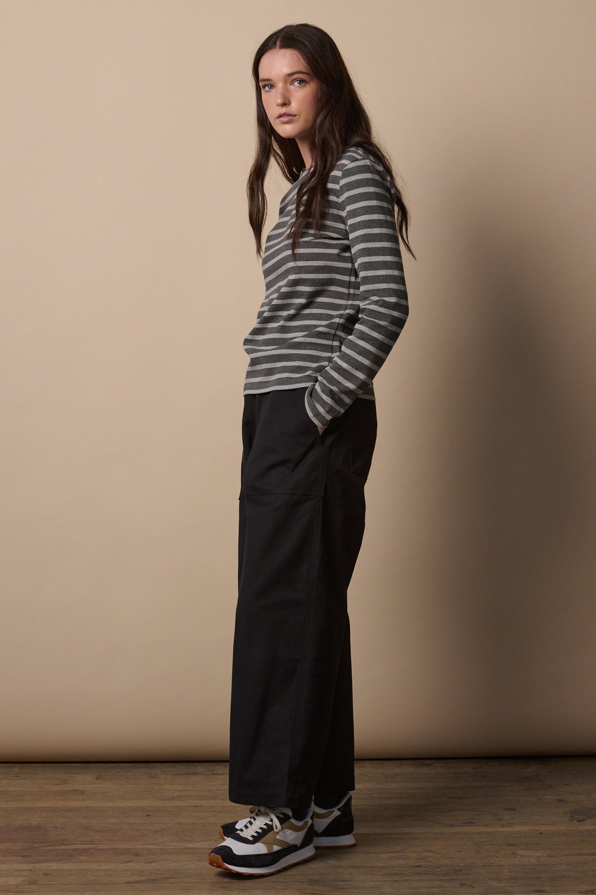 full body image showing the side of brunette female wearing camerawoman trousers in black