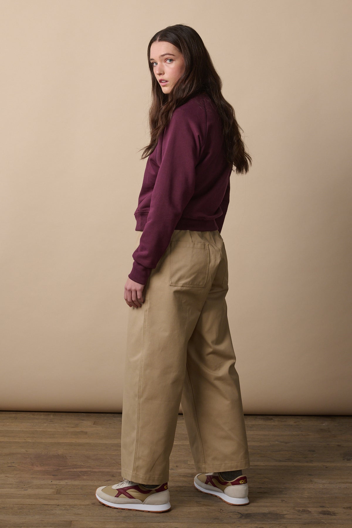 
            Image of female turned away from the camera showing the back of the wide tapered camerawoman drawstring trousers in putty. Two back pockets