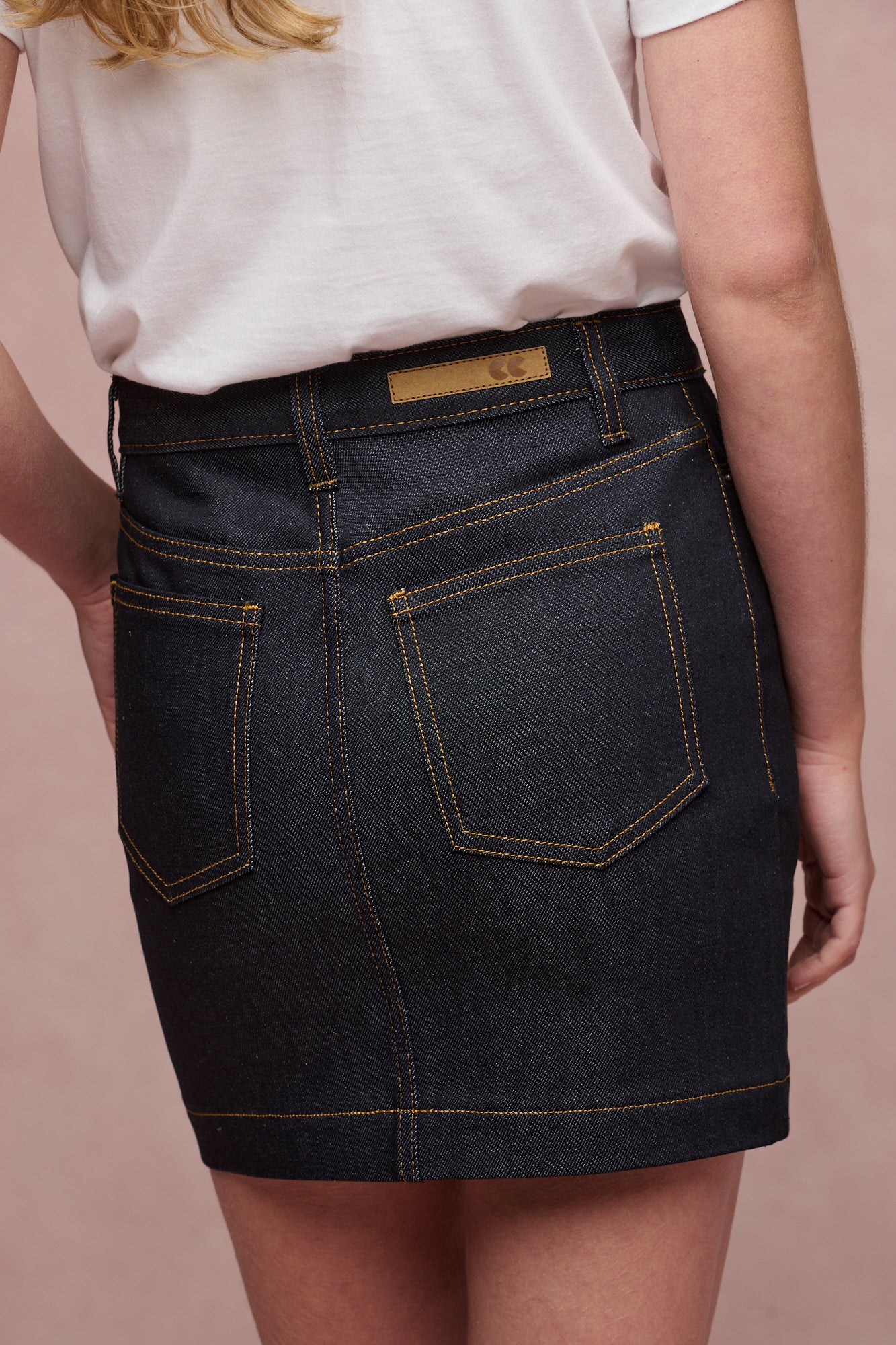 close up of the back of Charlie denim mini skirt in indigo, two back pockets and belt loops. CC logo jean patch