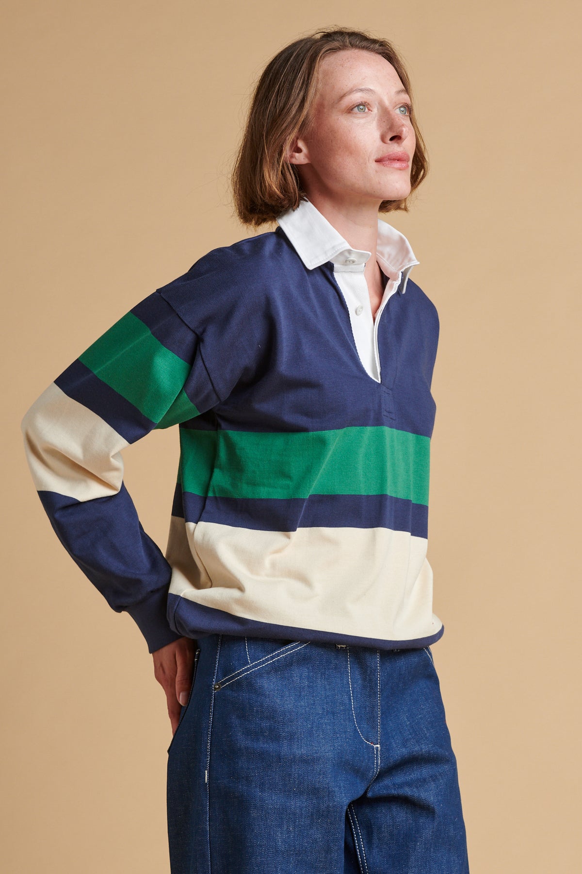 Female wearing chest stripe rugby shirt in navy ecru bottle green.