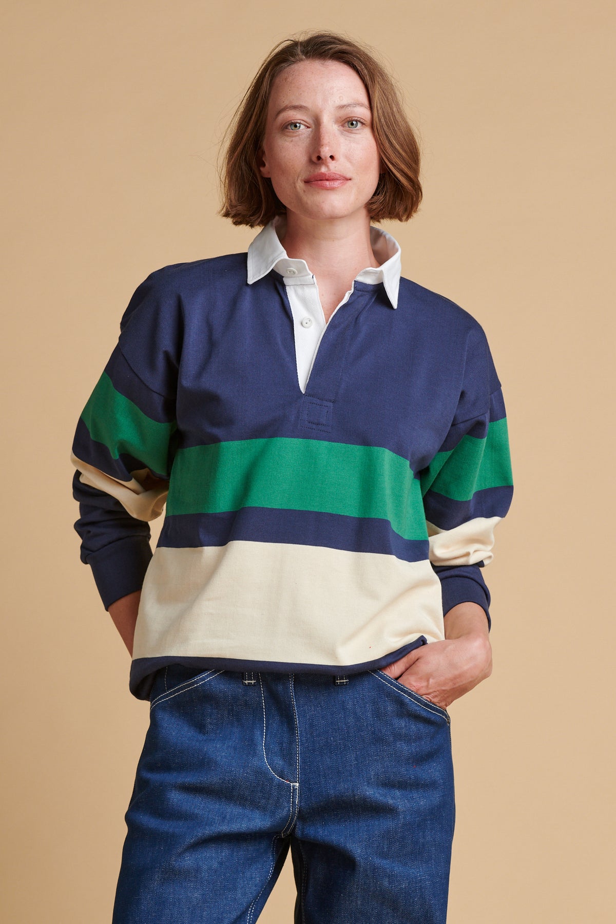 Female wearing chest stripe rugby shirt in navy ecru bottle green.