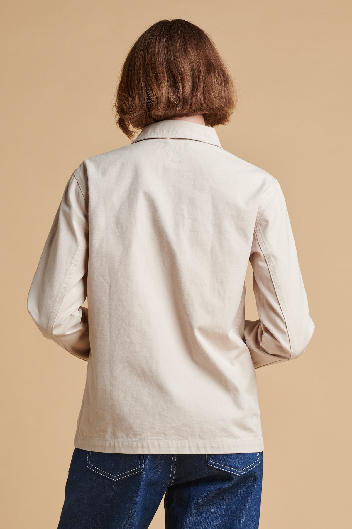 The back of female wearing chore jacket in cream.