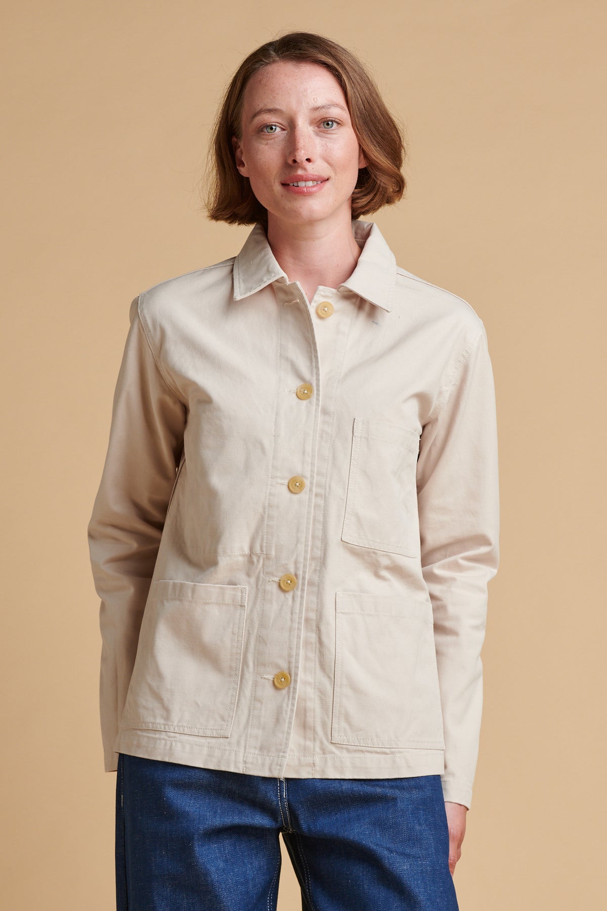 Female wearing chore jacket in cream.