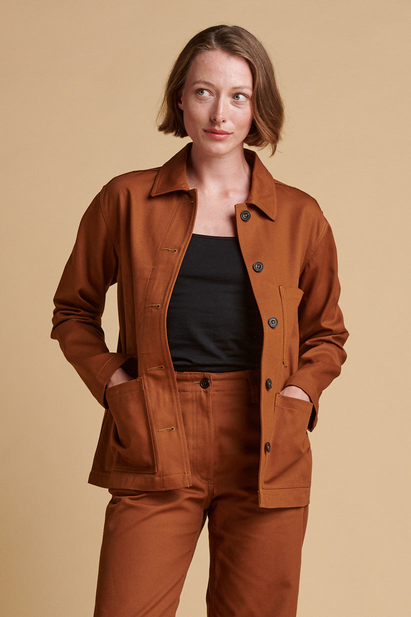 Female wearing chore jacket in dark tan unbuttoned over camisol ein black.