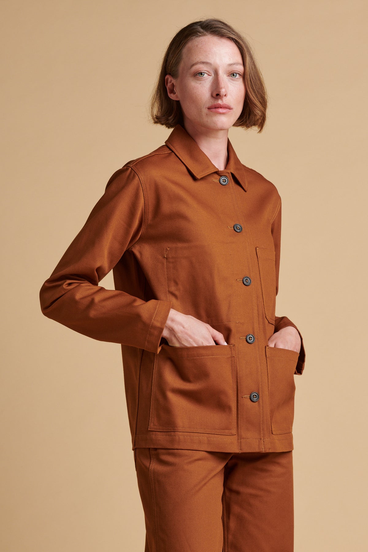 Female wearing chore jacket in dark tan.