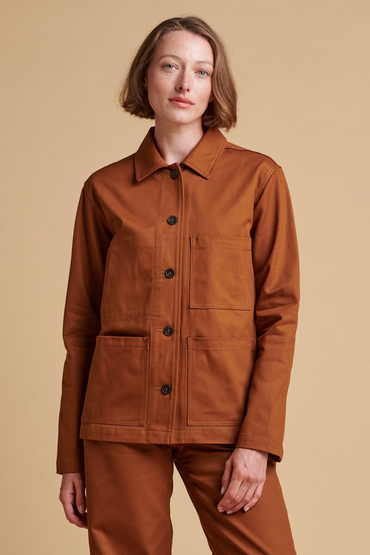 Female wearing chore jacket in dark tan.