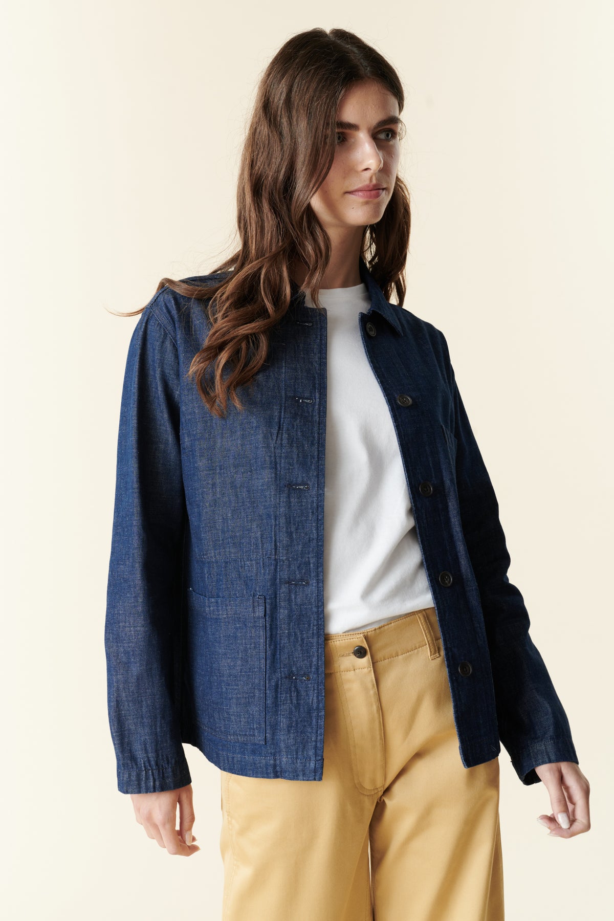Front, thigh up image of brunette female wearing chore jacket in denim