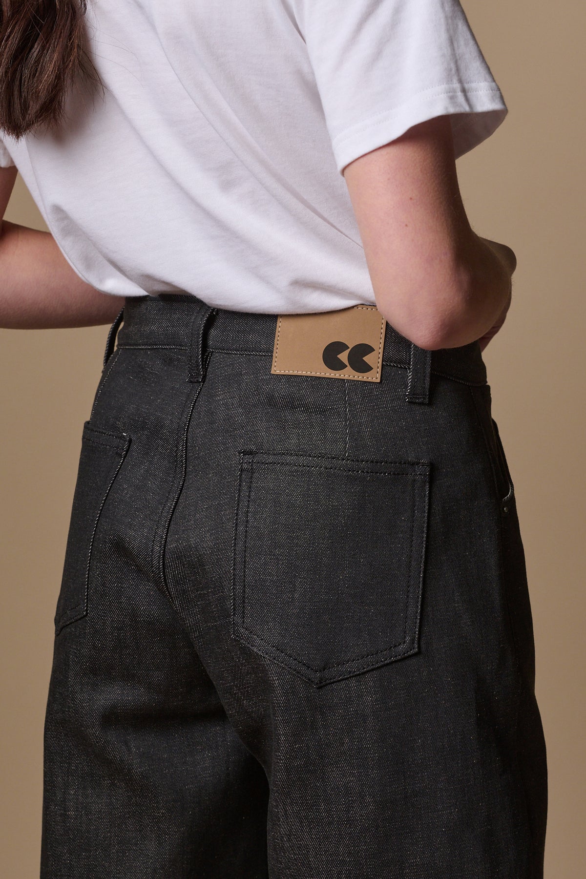 
            Detail shot of the back of women&#39;s chore jeans in black, showing brown jean patch with CC logo and belt loops, also two back pockets
