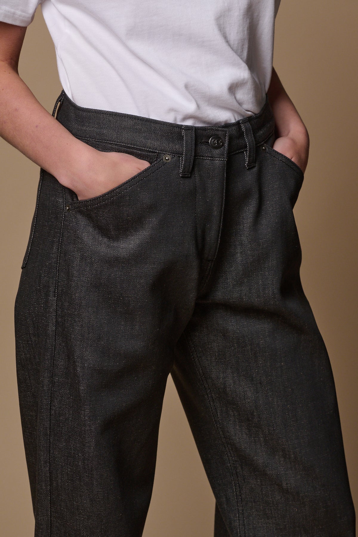 Close up of the front of women's chore jeans in black with models hands in the two front pockets.